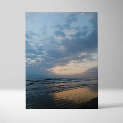 Vertical canvas wall art of a moody beach sunset with reflective wet sand and cloudy sky.