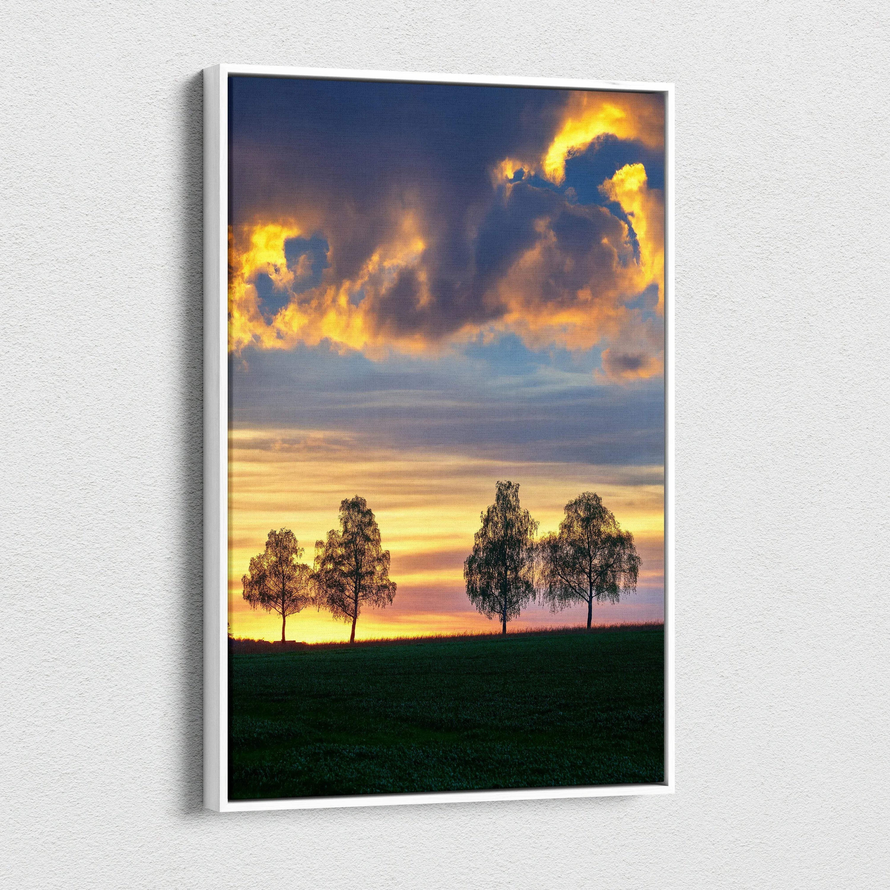 Vertical canvas wall art featuring a vibrant sunset sky with silhouetted trees over a grassy field.