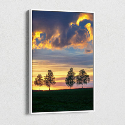 Vertical canvas wall art featuring a vibrant sunset sky with silhouetted trees over a grassy field.