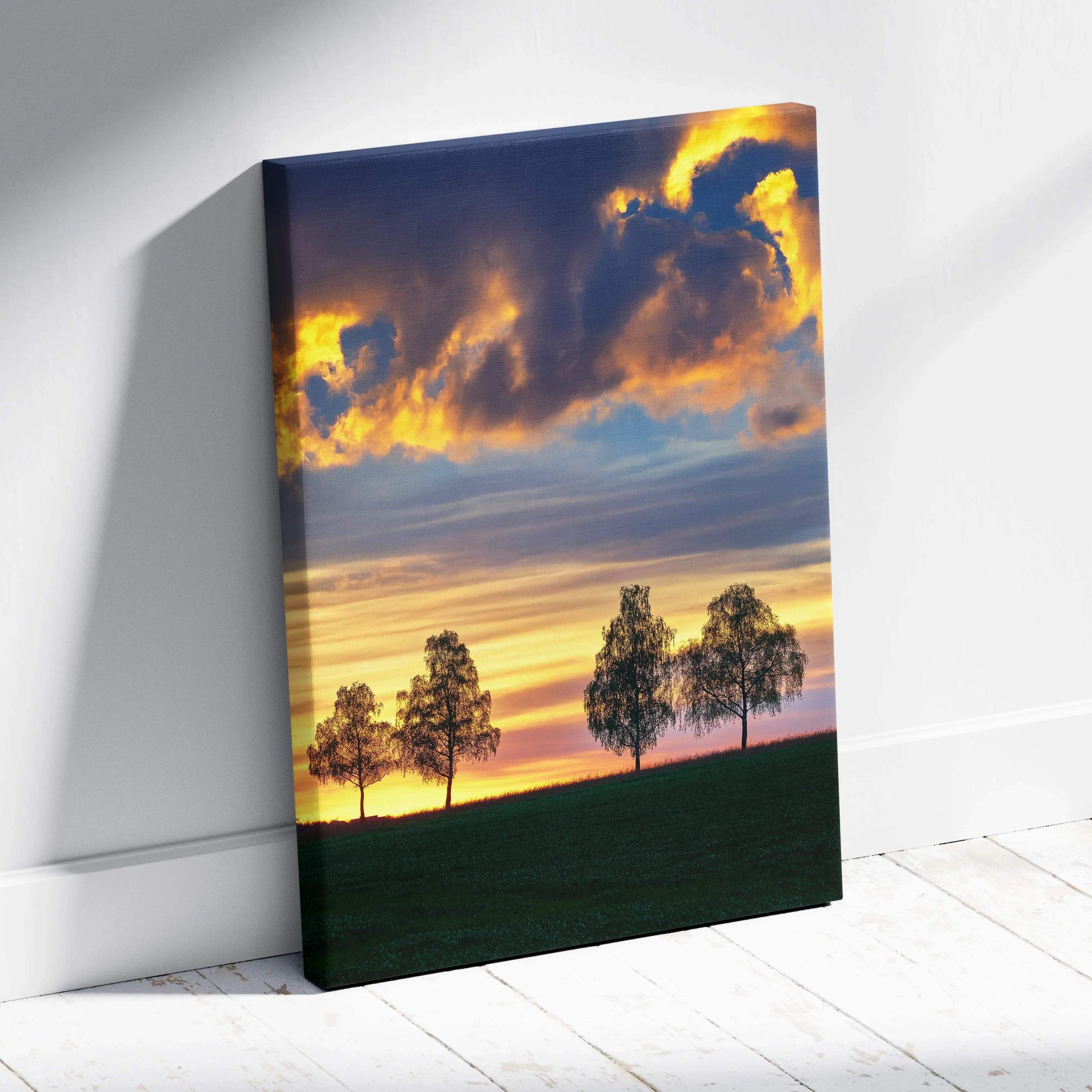 Sunset landscape canvas wall art with vibrant orange and blue sky above silhouetted trees and dark green field.
