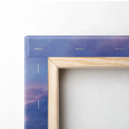 Close-up of natural wood frame corner on canvas wall art with blue and purple sunset sky design.