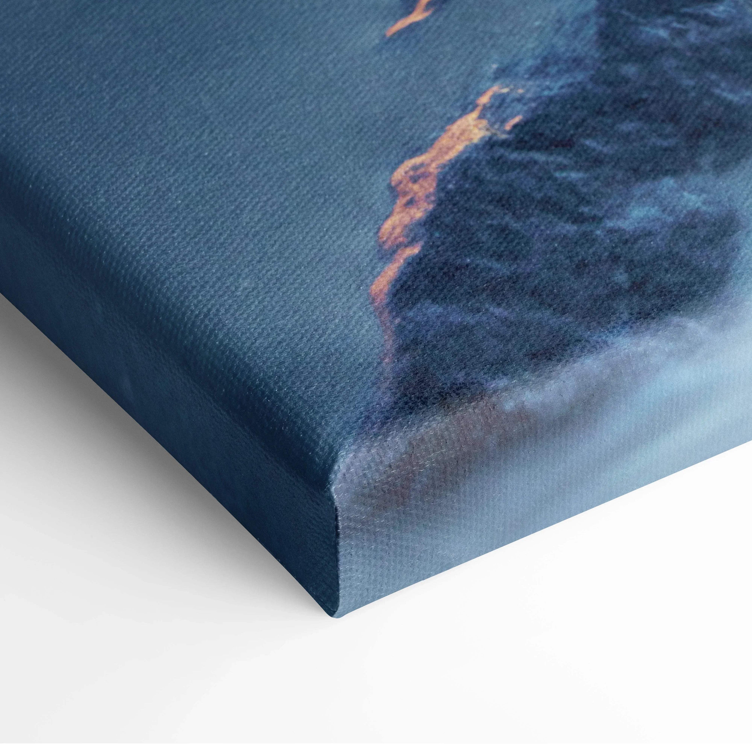 Close-up of textured canvas wall art print featuring a peaceful beach sunset with deep blue and orange hues.