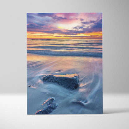 Canvas wall art of a tranquil beach sunset with soft pastel skies and waves flowing around rocks.