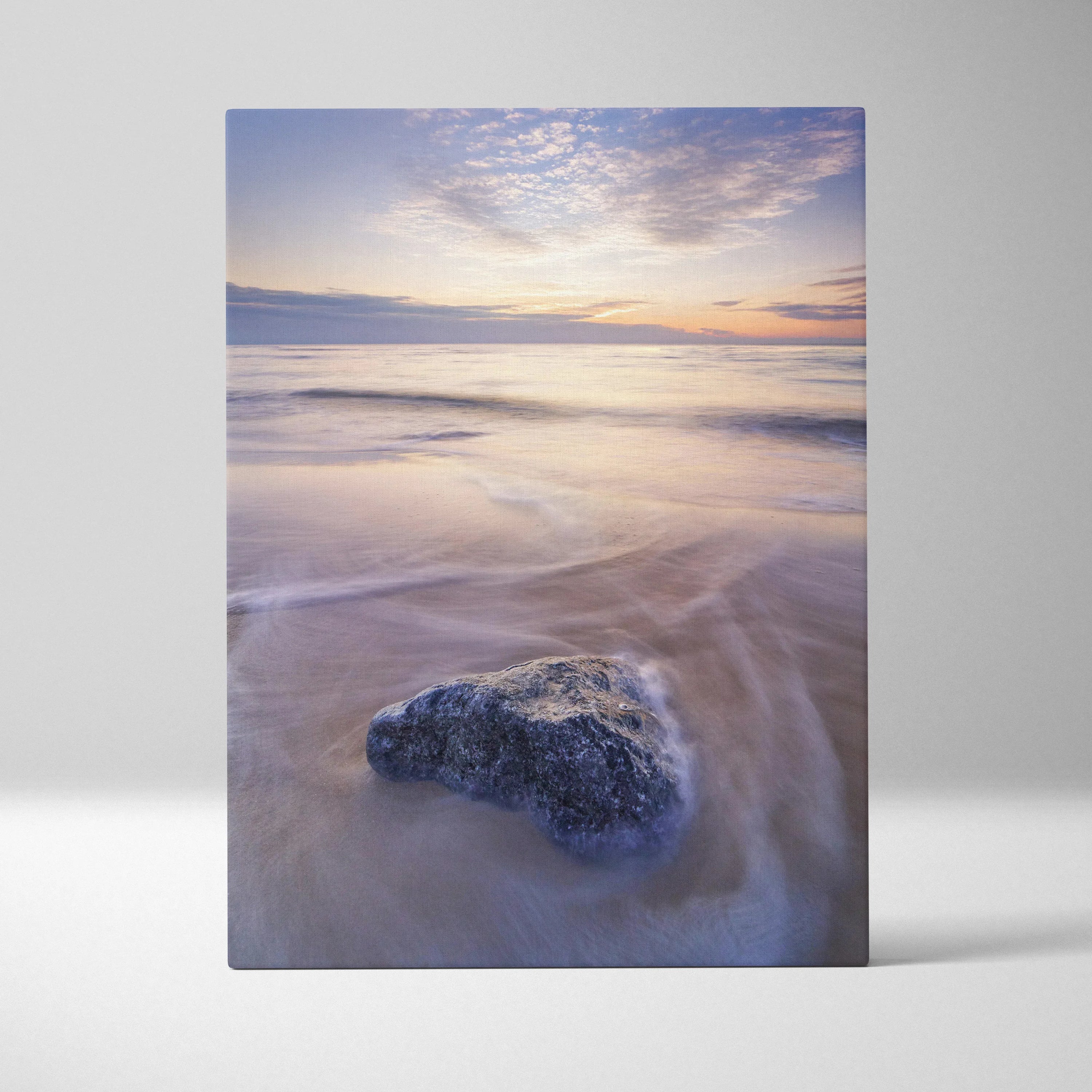Serene beach sunset canvas wall art featuring soft pastel sky and a single rock on smooth wet sand.