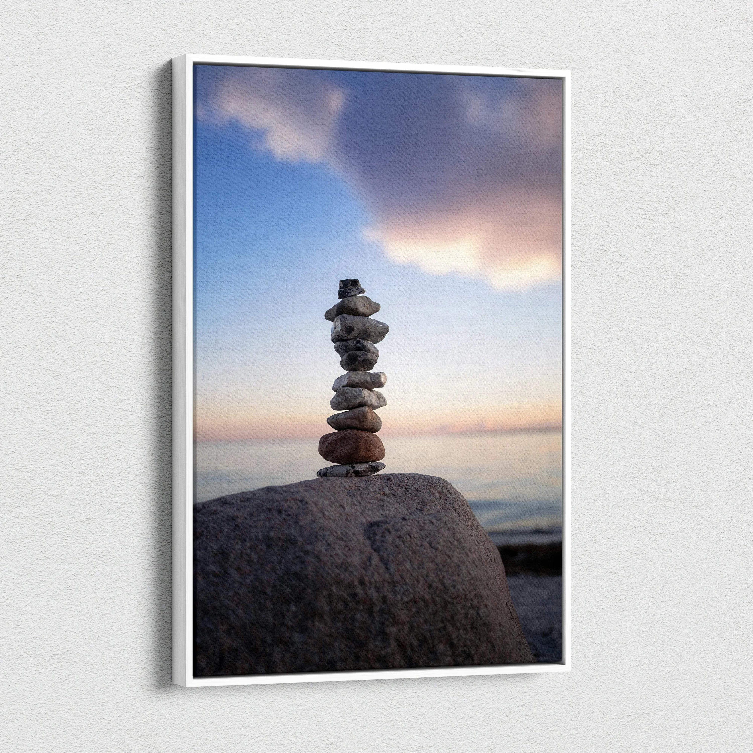 Vertical canvas wall art of stacked stones on a beach with a colorful sunset sky.