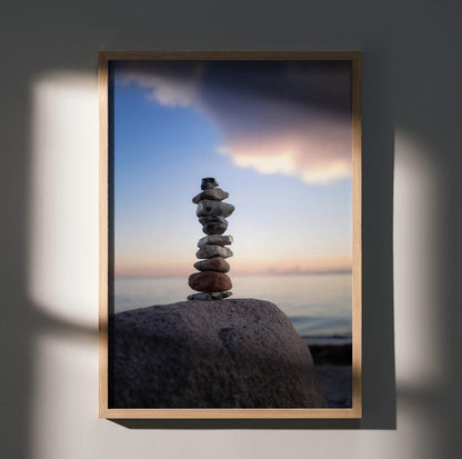 Serene nature landscape wall art poster featuring balanced stones on a large rock at sunset.