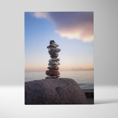 Canvas wall art featuring balanced beach stones at sunset with soft clouds and calm water backdrop.