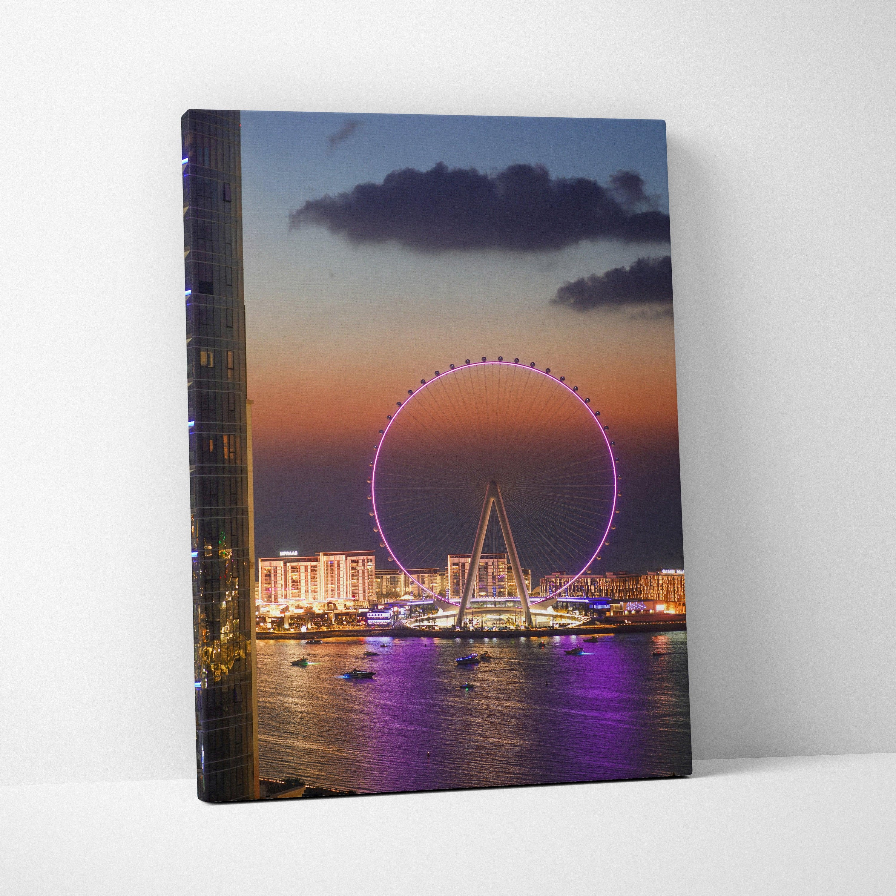Vertical canvas wall art of vibrant cityscape at sunset featuring illuminated Ferris wheel and waterfront buildings.