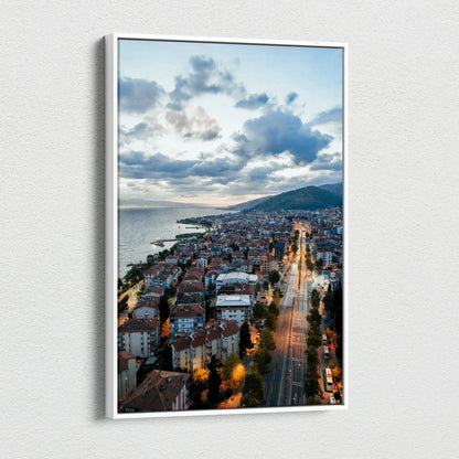 Vibrant city sunset canvas wall art showing illuminated buildings and streets along the coastline.