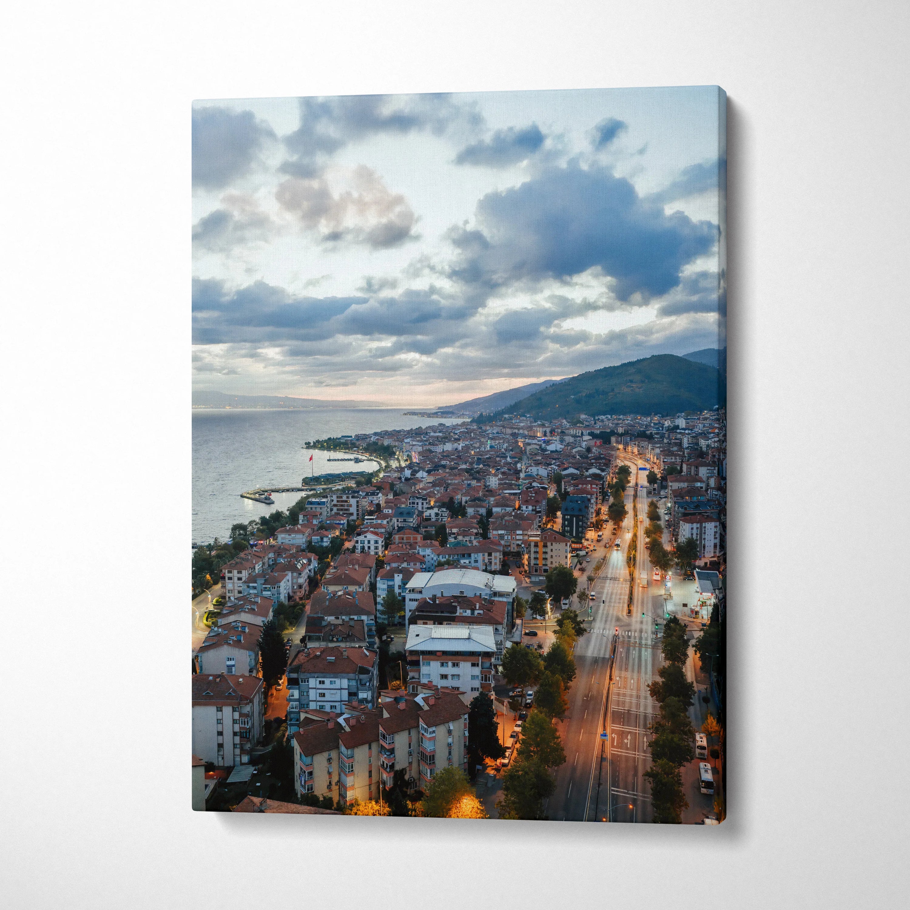 Canvas wall art featuring a cityscape at sunset with illuminated buildings and streets beneath a cloudy sky.