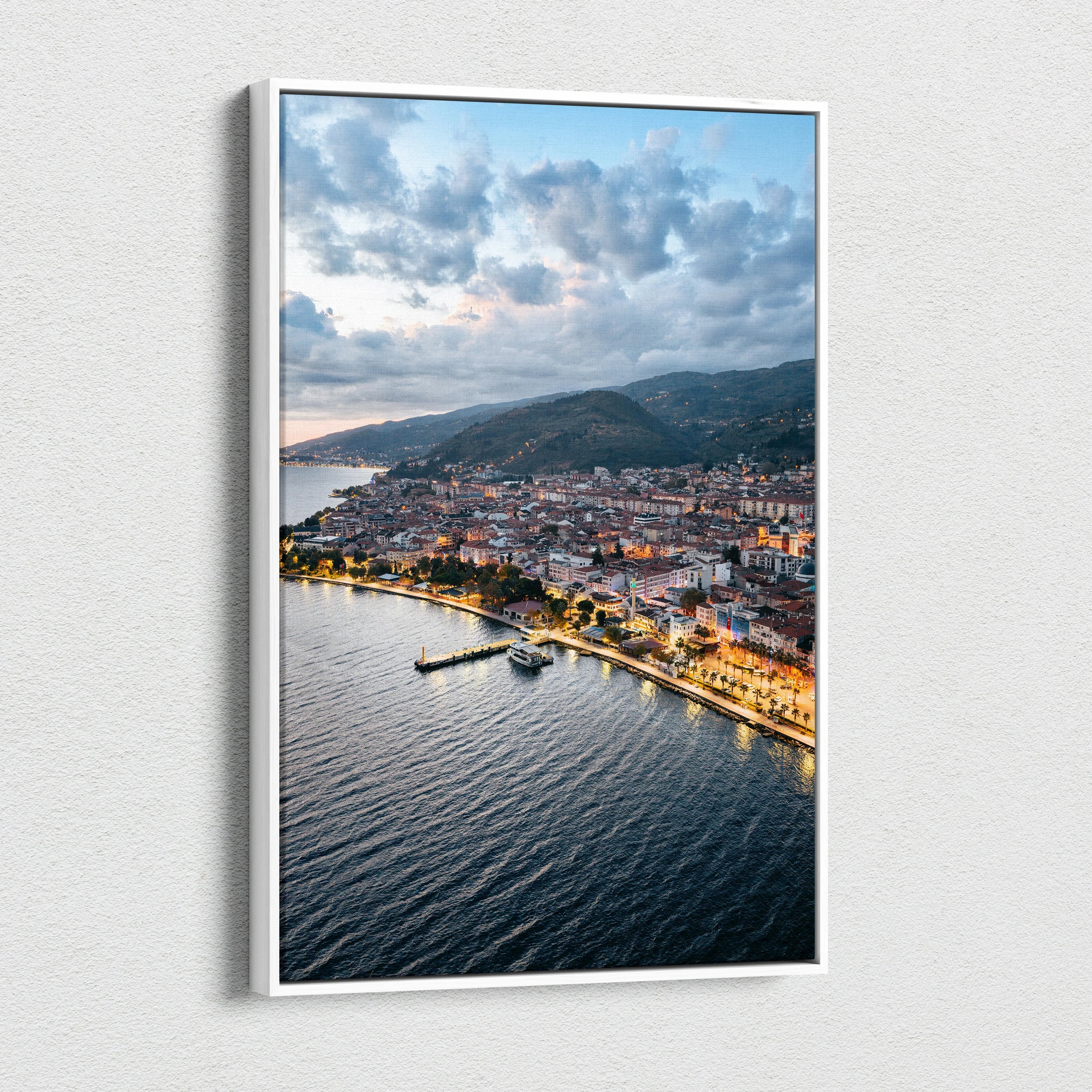 Vertical canvas wall art featuring a vibrant city sunset over coastal buildings and water.