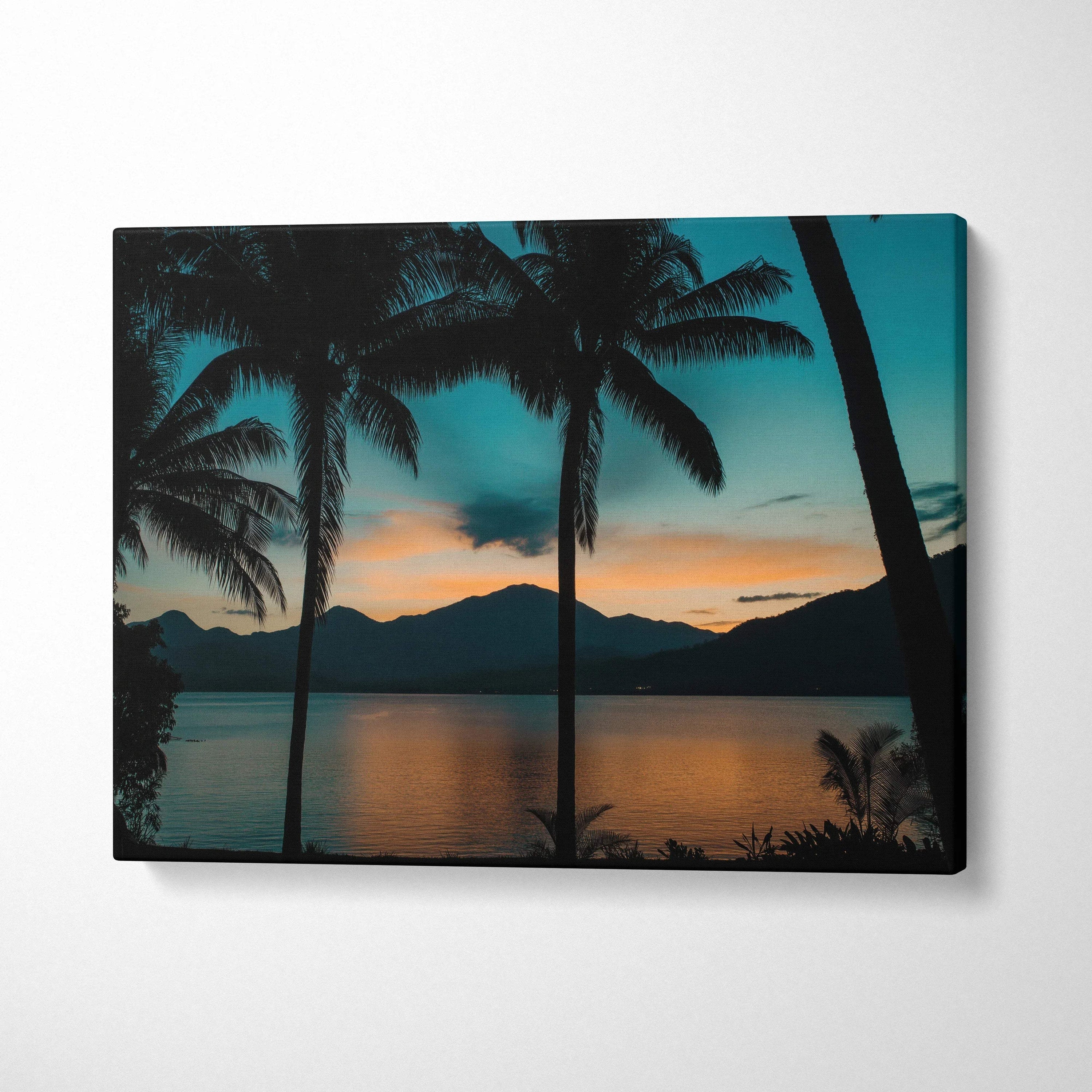 Canvas print of silhouetted palm trees at tranquil mountain lake dusk in teal orange sunset