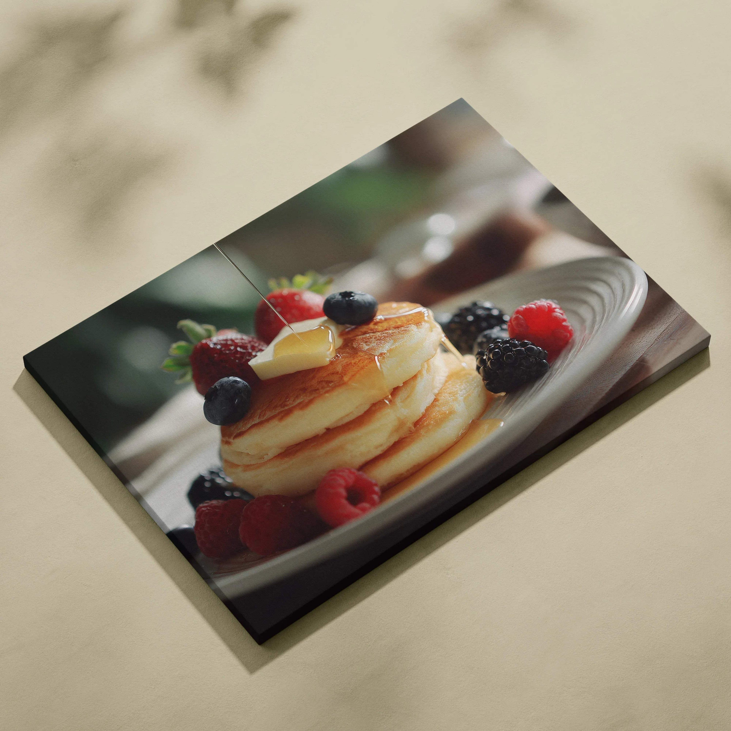 Canvas wall art depicting stacked golden pancakes topped with mixed fresh berries and syrup on a white plate.