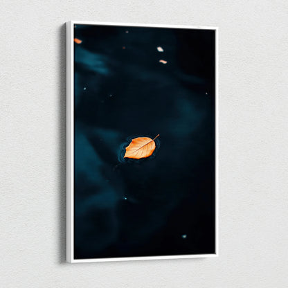 Minimalist autumn leaf floating on dark water canvas wall art print in vertical white frame.