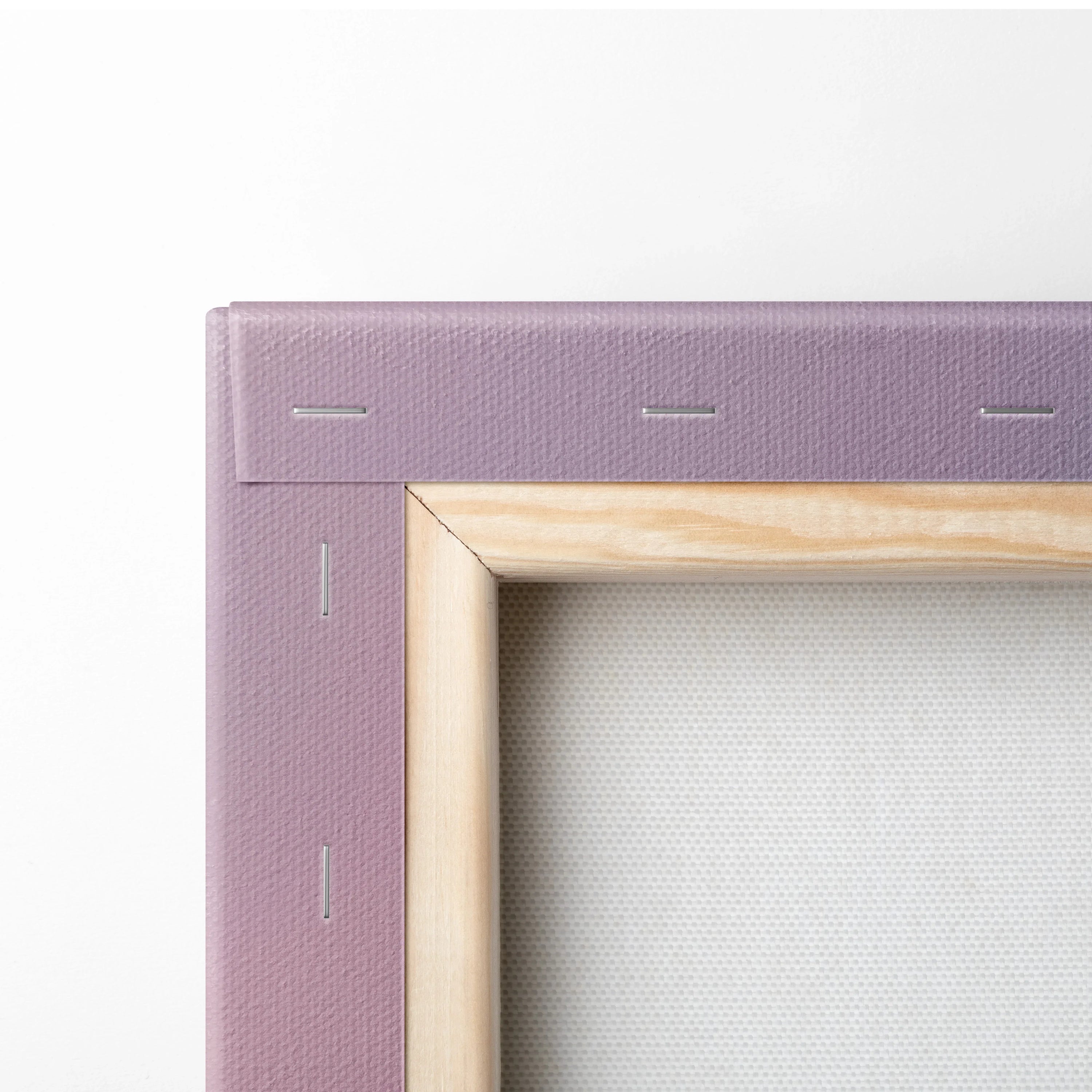 Close-up of a wooden frame corner wrapped in textured pink canvas with visible staples securing the material.