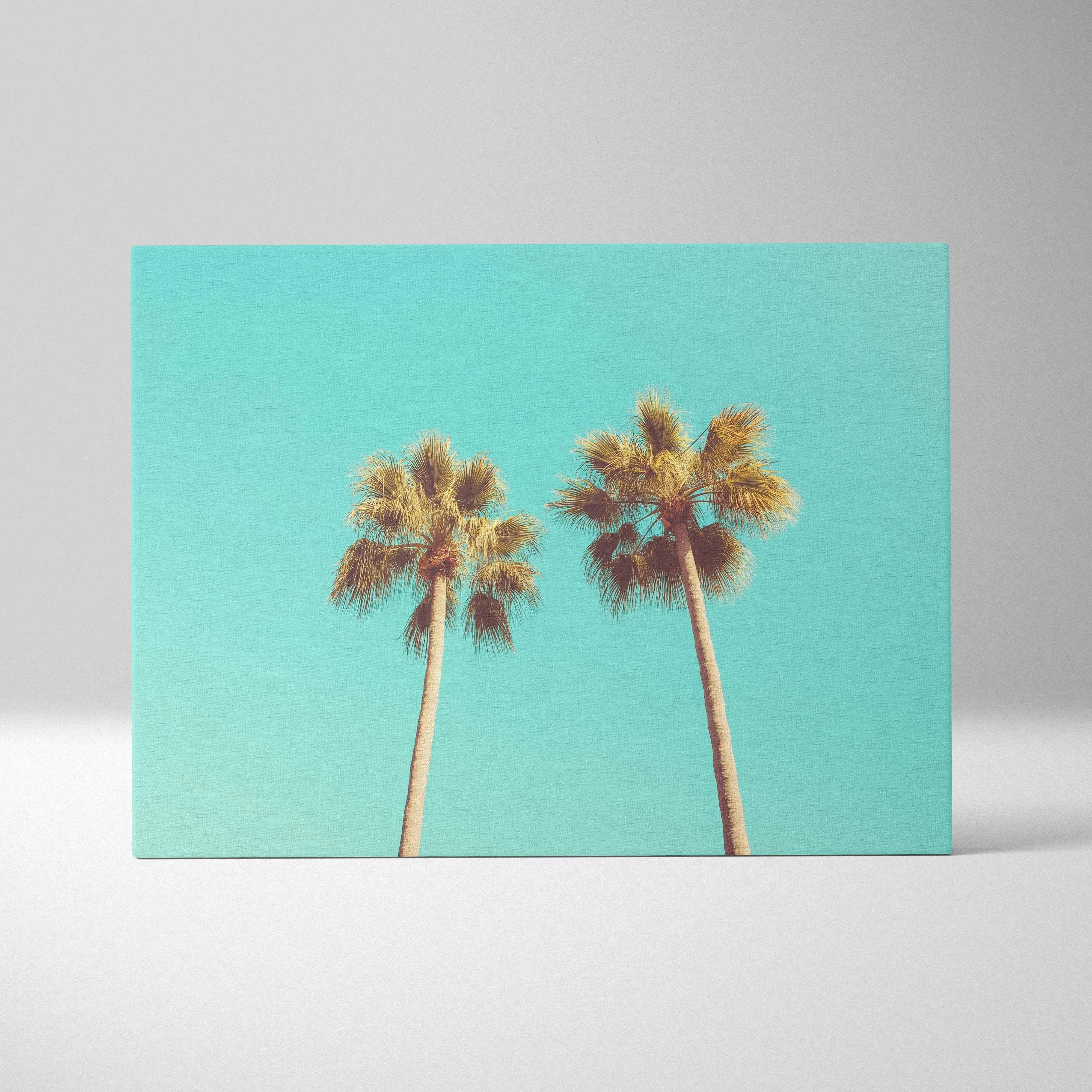 Rectangular canvas print of two tall palm trees with golden fronds against a vibrant turquoise sky for coastal decor