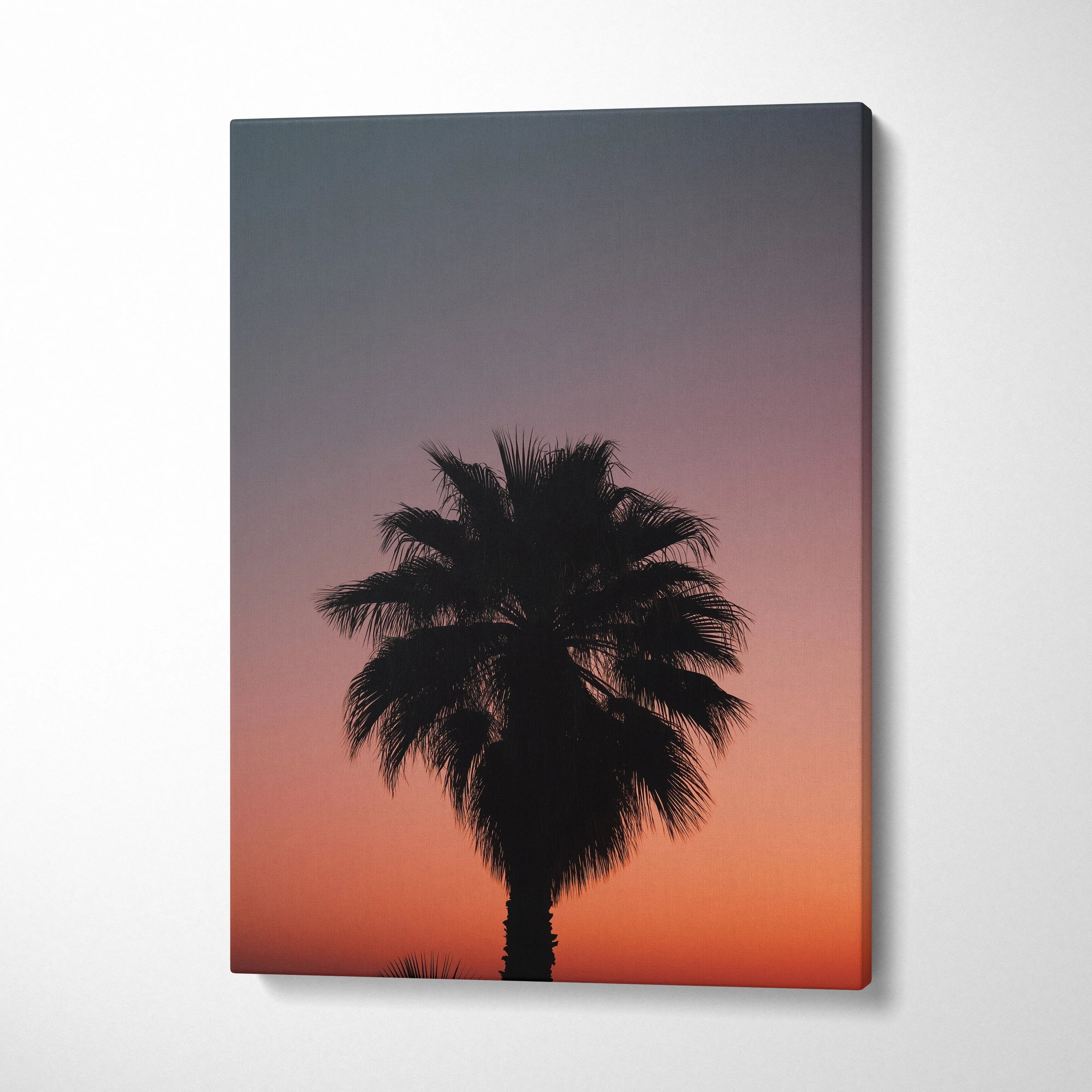 Canvas wall art featuring a black silhouette of a tropical palm tree against a vivid dusk sky with gradient orange and.