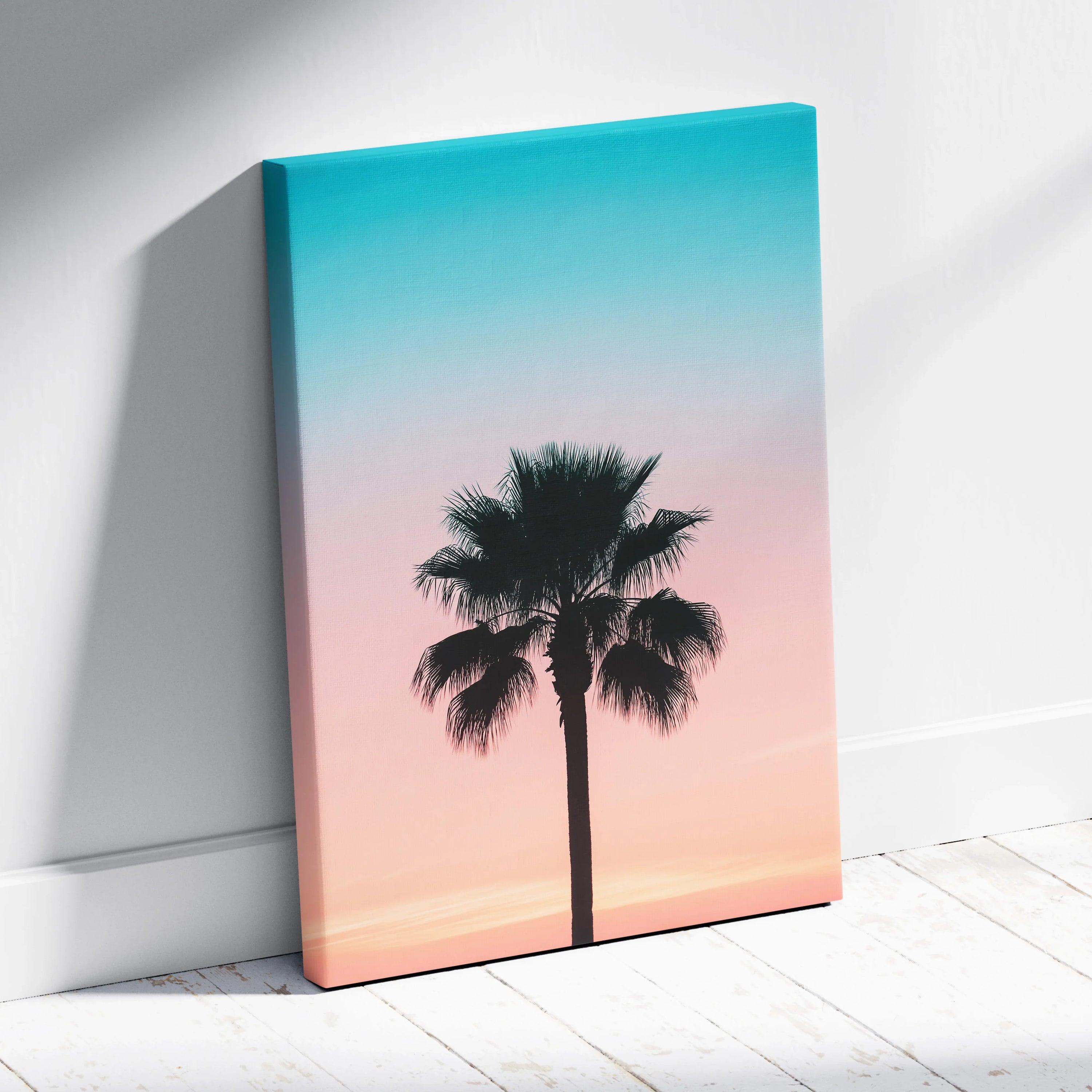 Canvas wall art featuring a black palm tree silhouette against a gradient sunset sky of turquoise and soft pink tones.