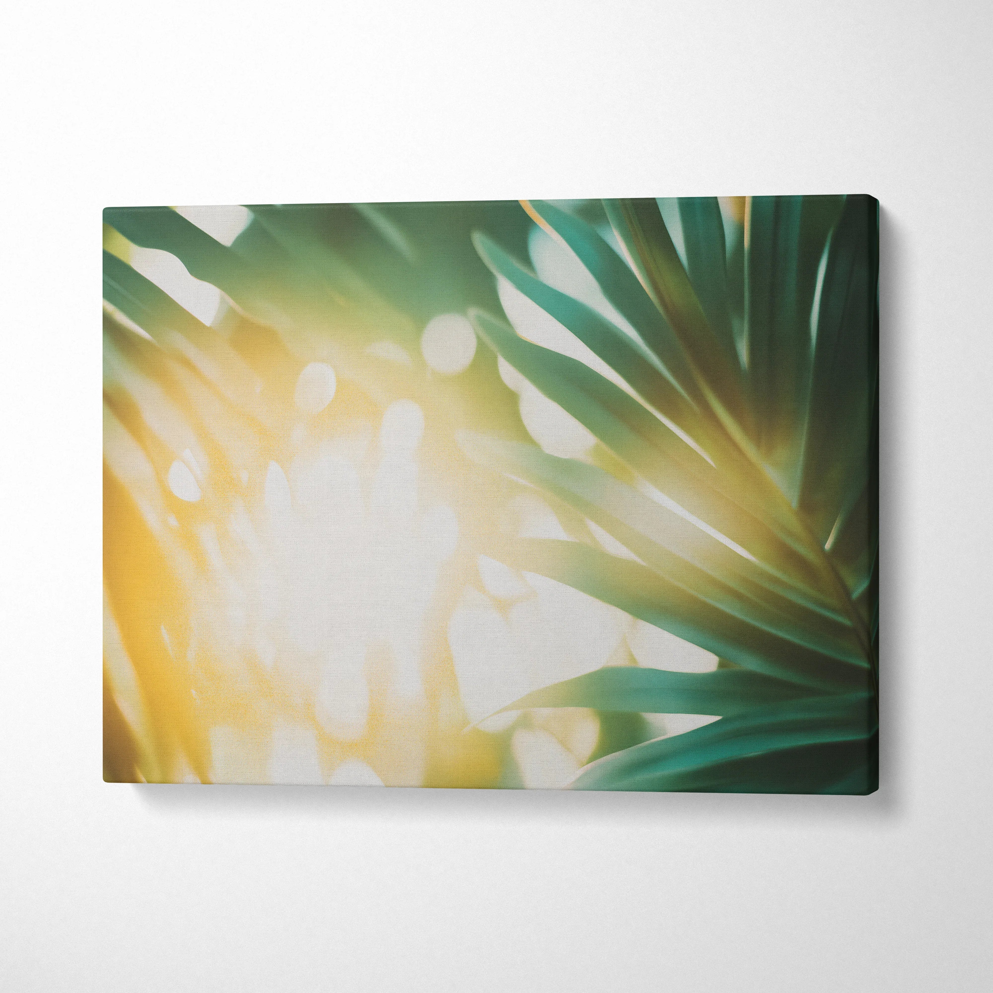 Tropical green leaves with warm golden sun flare on horizontal canvas wall art decor.
