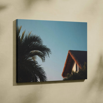 Tropical canvas wall art featuring palm trees and a thatched roof house against a clear blue sky.