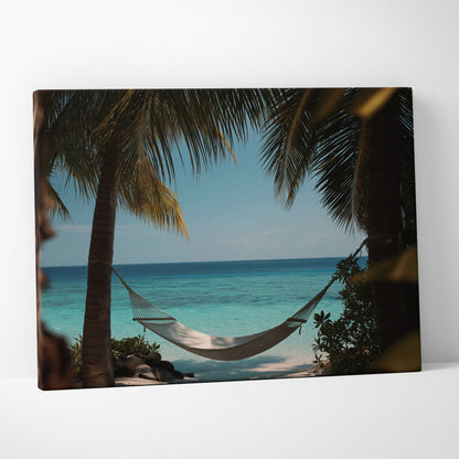 Canvas wall art featuring a white hammock strung between palm trees with a turquoise ocean and blue sky background.