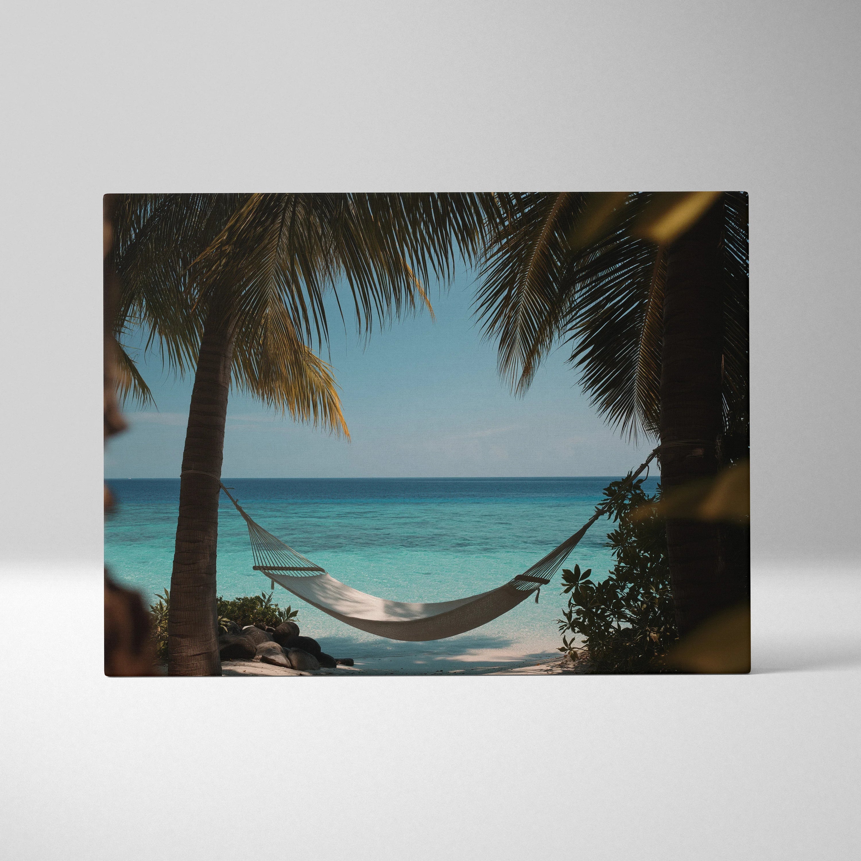 Canvas wall art showing a white hammock between palm trees with a turquoise ocean and blue sky background.
