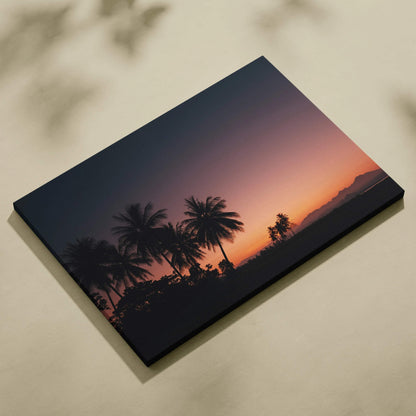 Canvas wall art featuring a tropical sunset with silhouetted palm trees against a dusk sky in warm orange and purple tones.