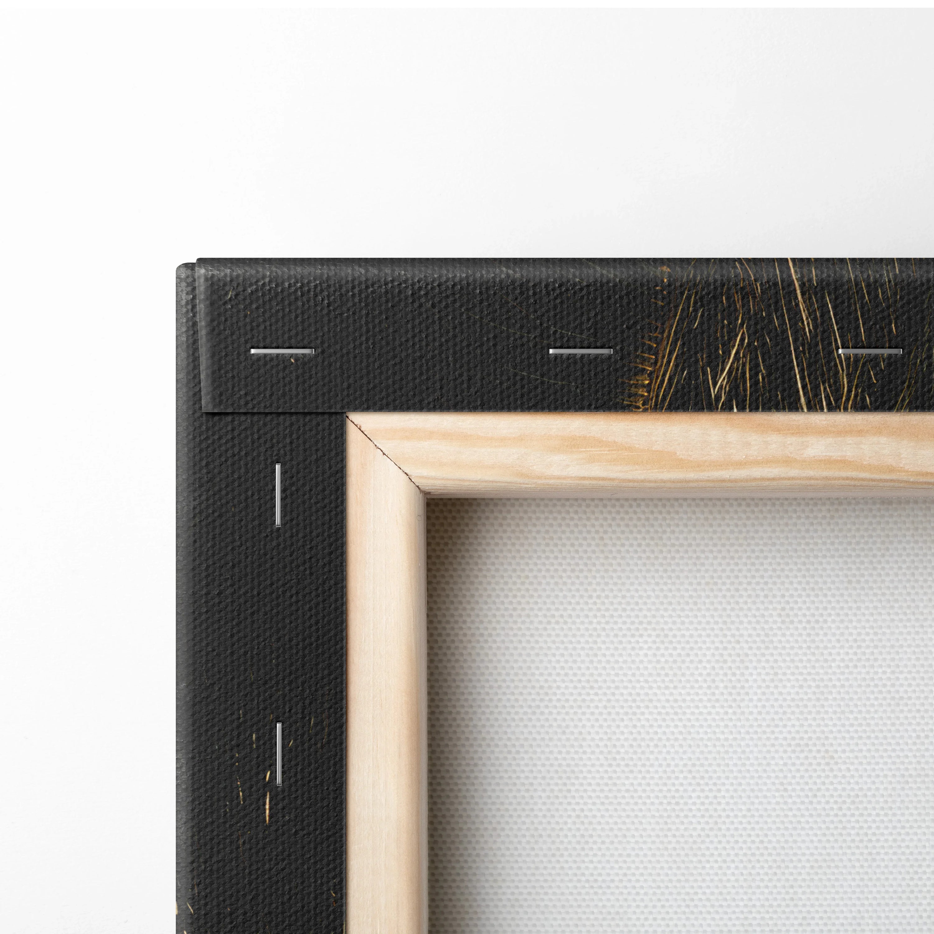 Wooden stretcher frame corner showing natural wood and black canvas backing with visible staples.