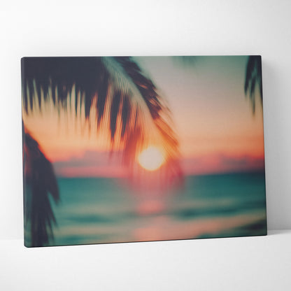 Canvas wall art featuring a blurred tropical sunset with orange and teal hues and silhouette palm leaves.