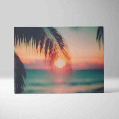 Canvas wall art featuring a blurred tropical sunset with warm orange, pink, and teal hues framed by silhouette palm leaves.