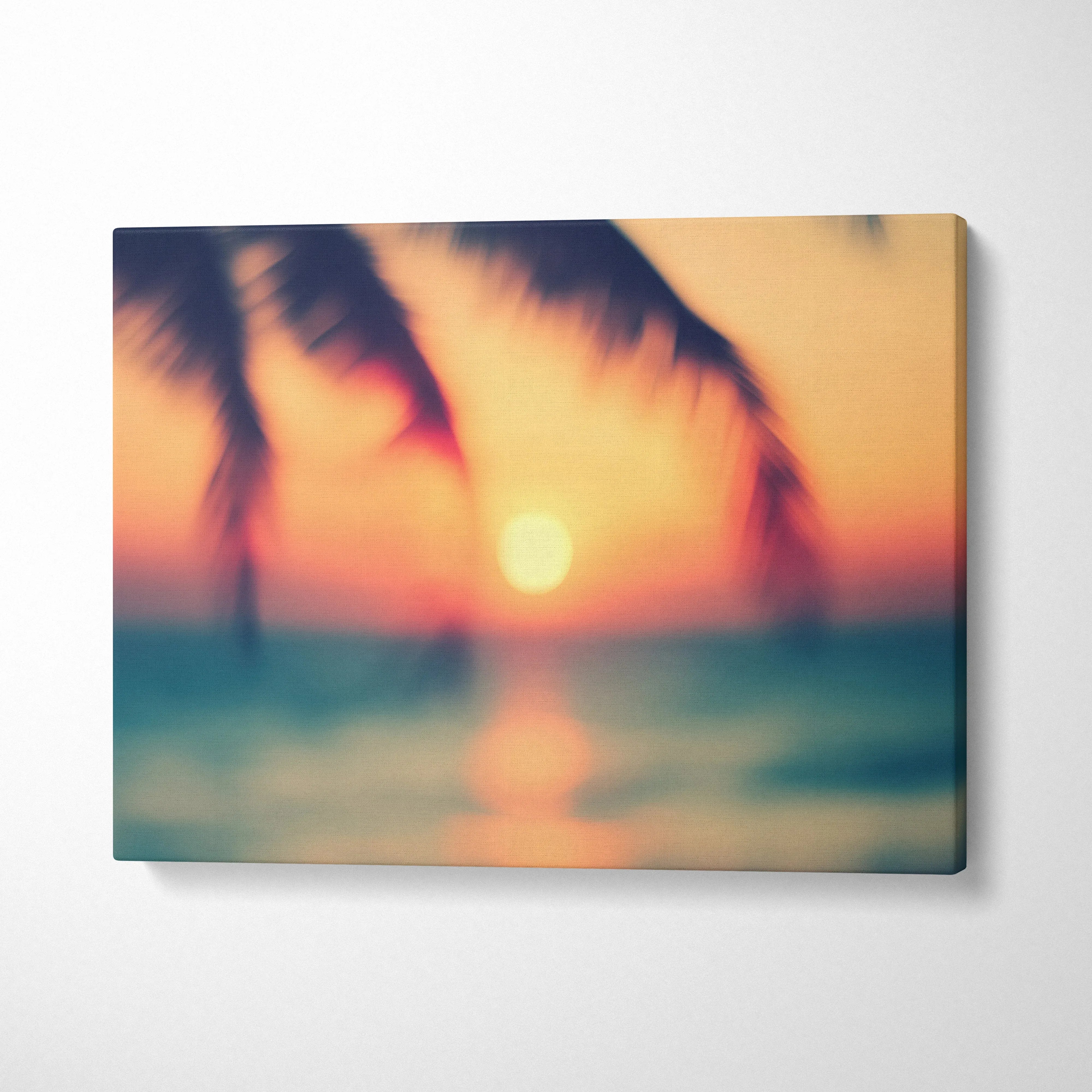Tropical sunset canvas wall art with blurred palm tree silhouettes and ocean glow decor.