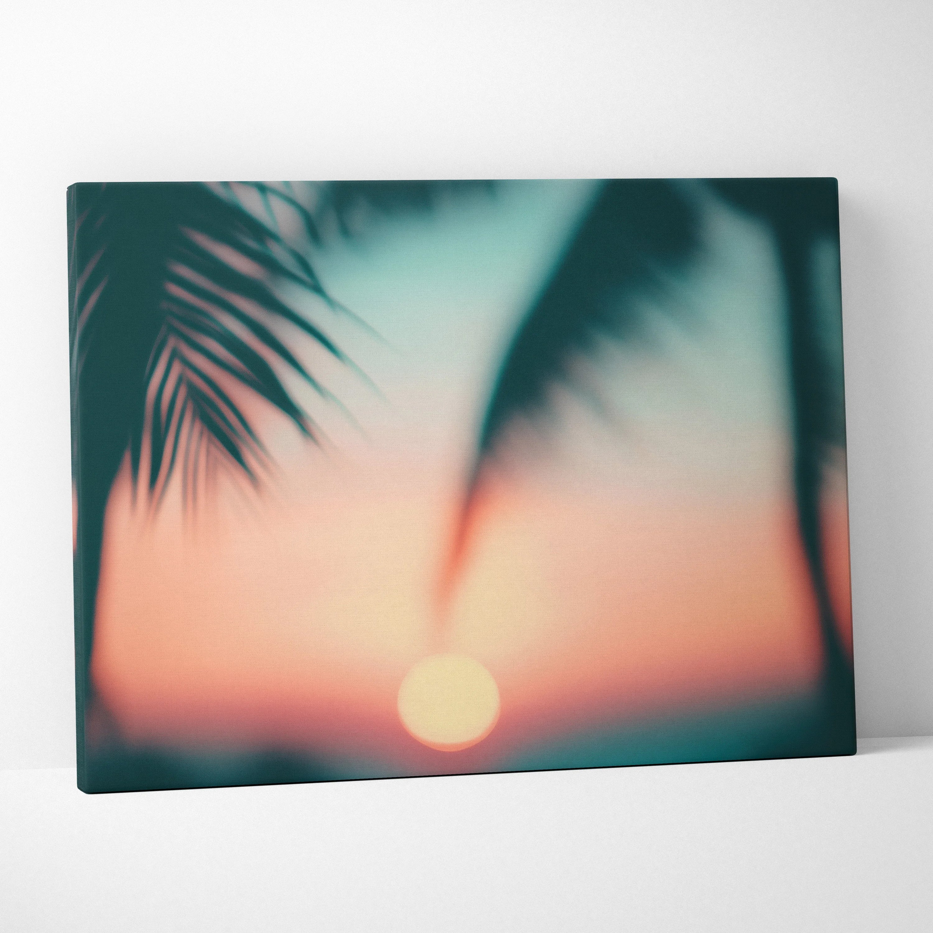 Canvas wall art featuring a blurred tropical sunset with a glowing sun and palm leaf silhouettes.