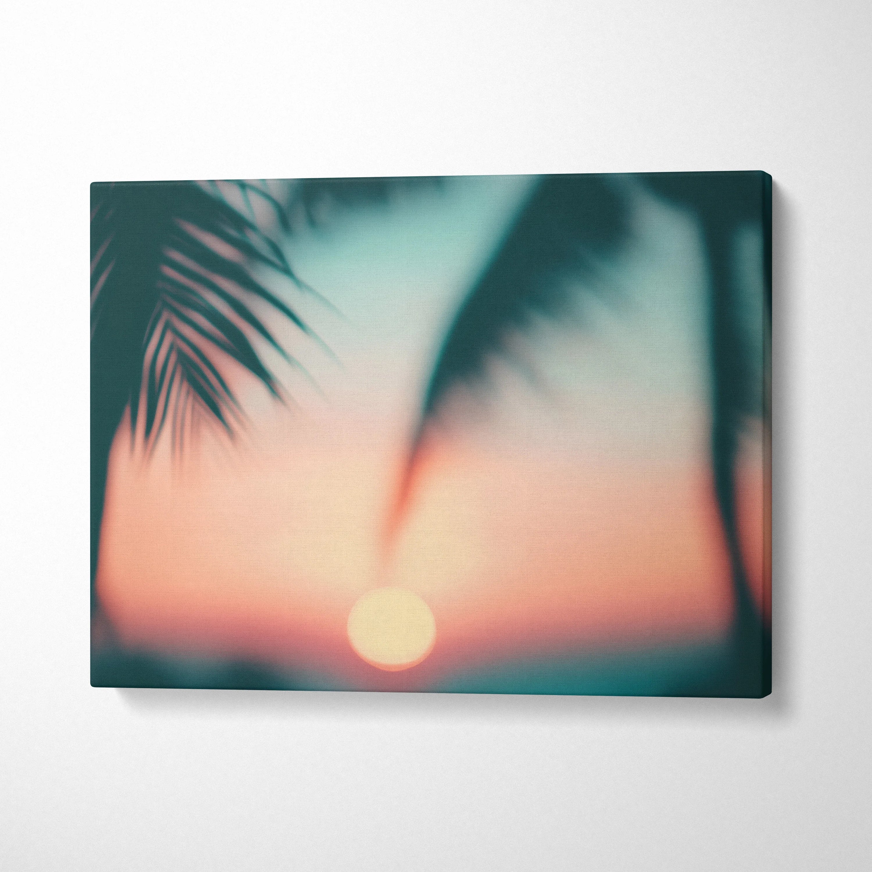 Tropical sunset canvas wall art with blurred palm silhouette leaves and soft orange sky decor.