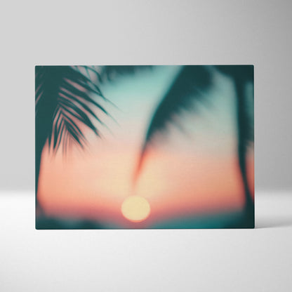 Canvas wall art featuring a soft-focus tropical sunset with palm leaf silhouettes in warm coral and teal tones.