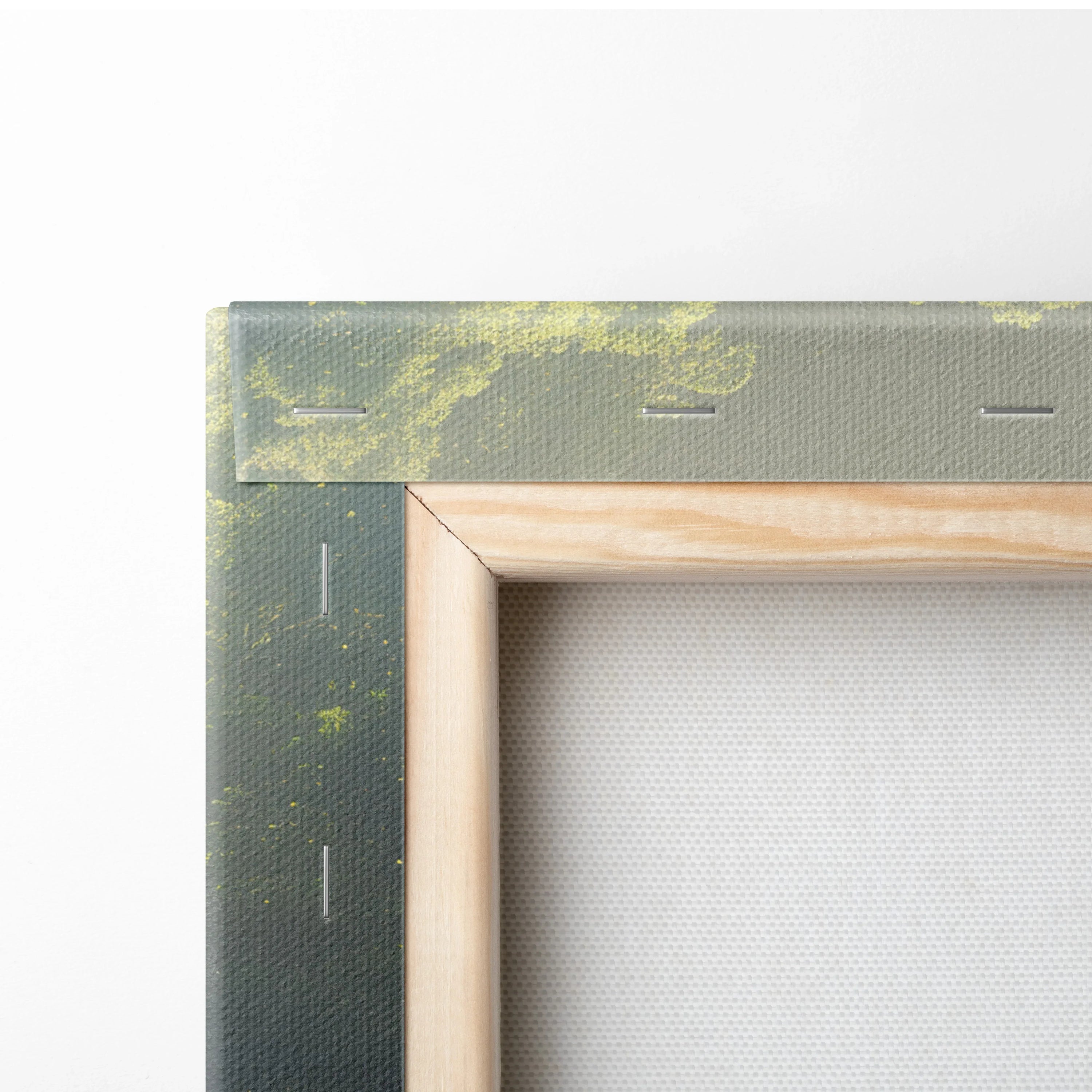Close-up of wooden frame corner and stretched canvas with nature waterfall print on textured fabric wall art.