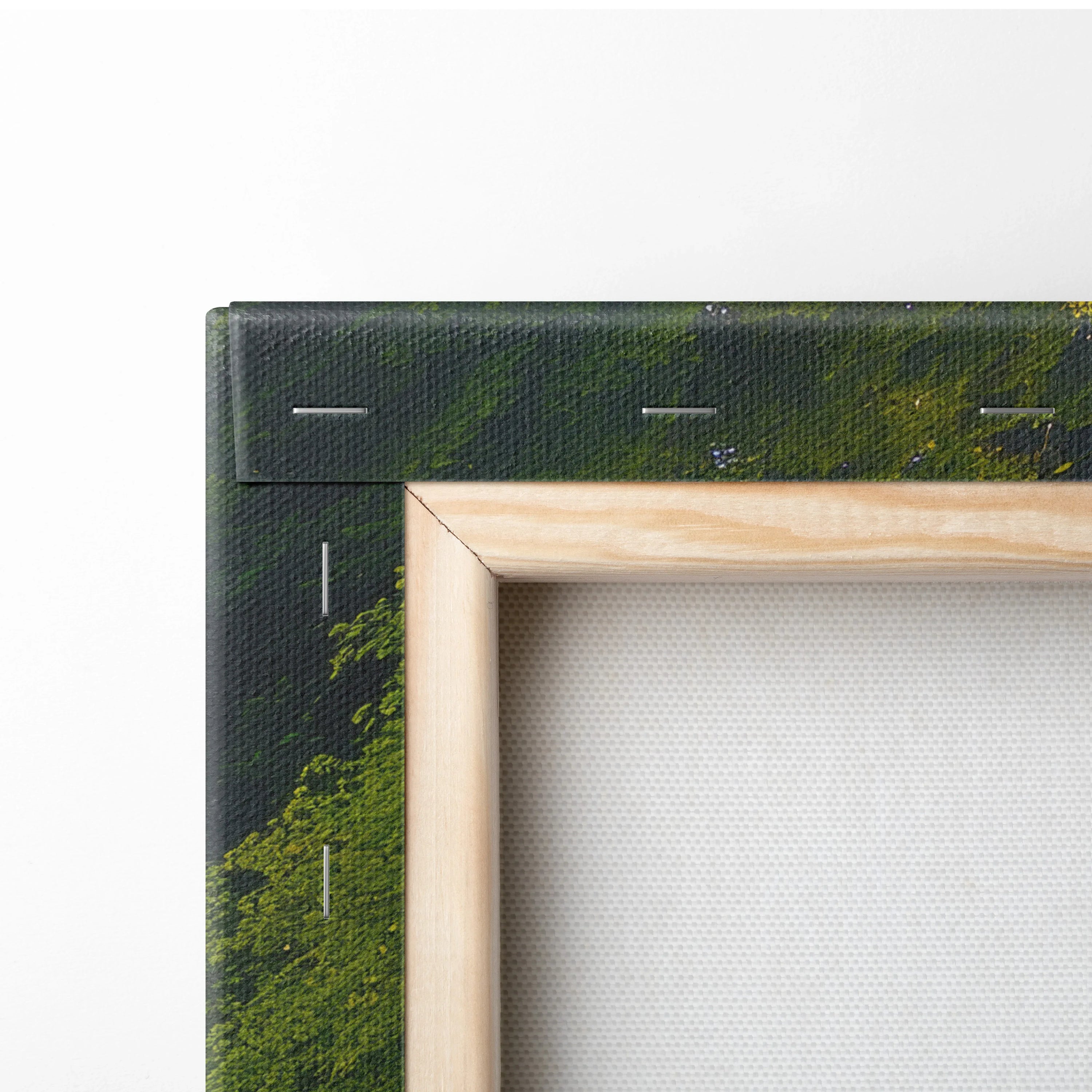 Close-up of wooden frame and black wrapped canvas corner with visible staples on textured white canvas wall art display.