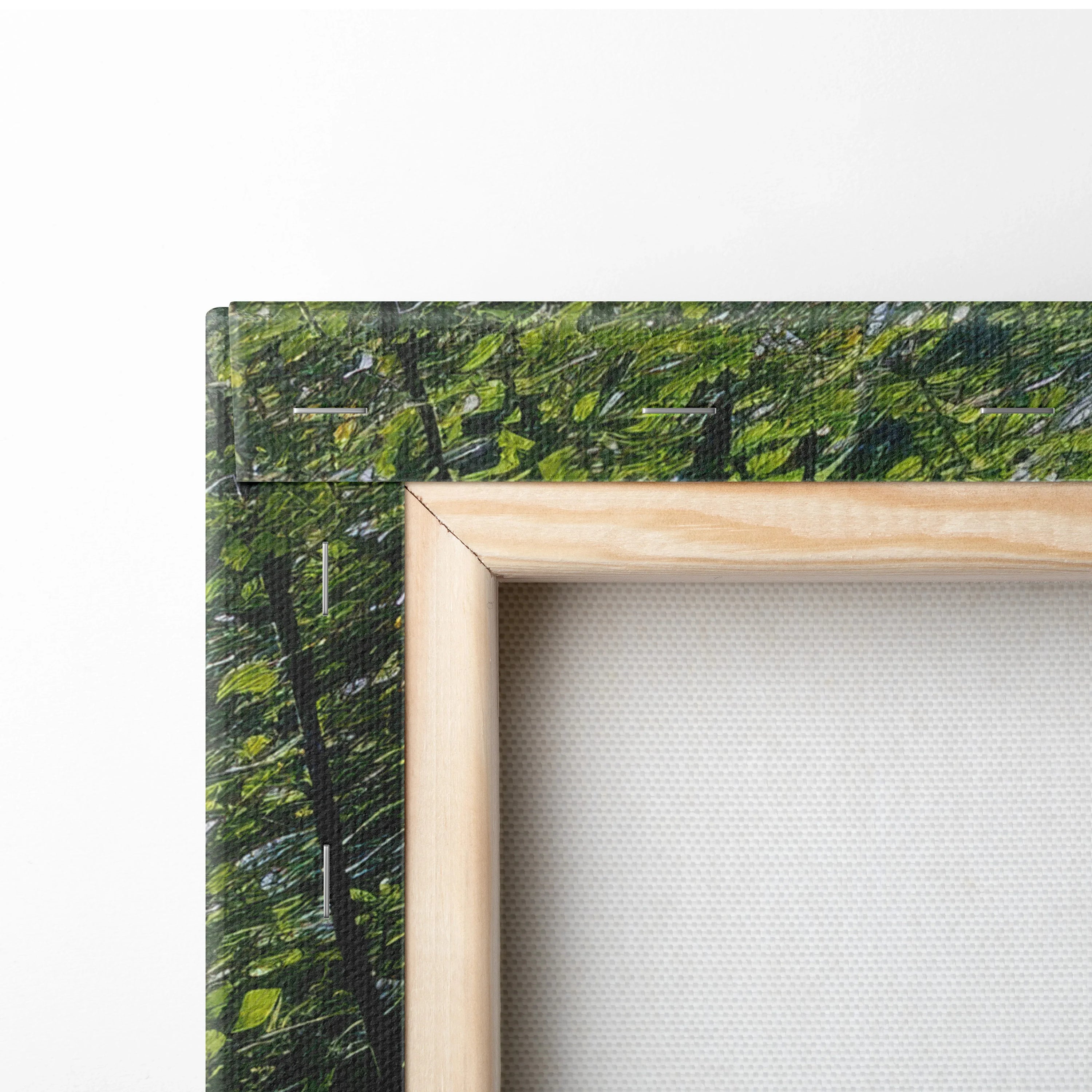 Natural wood frame corner with green leafy canvas texture and blank white interior wall art decor.