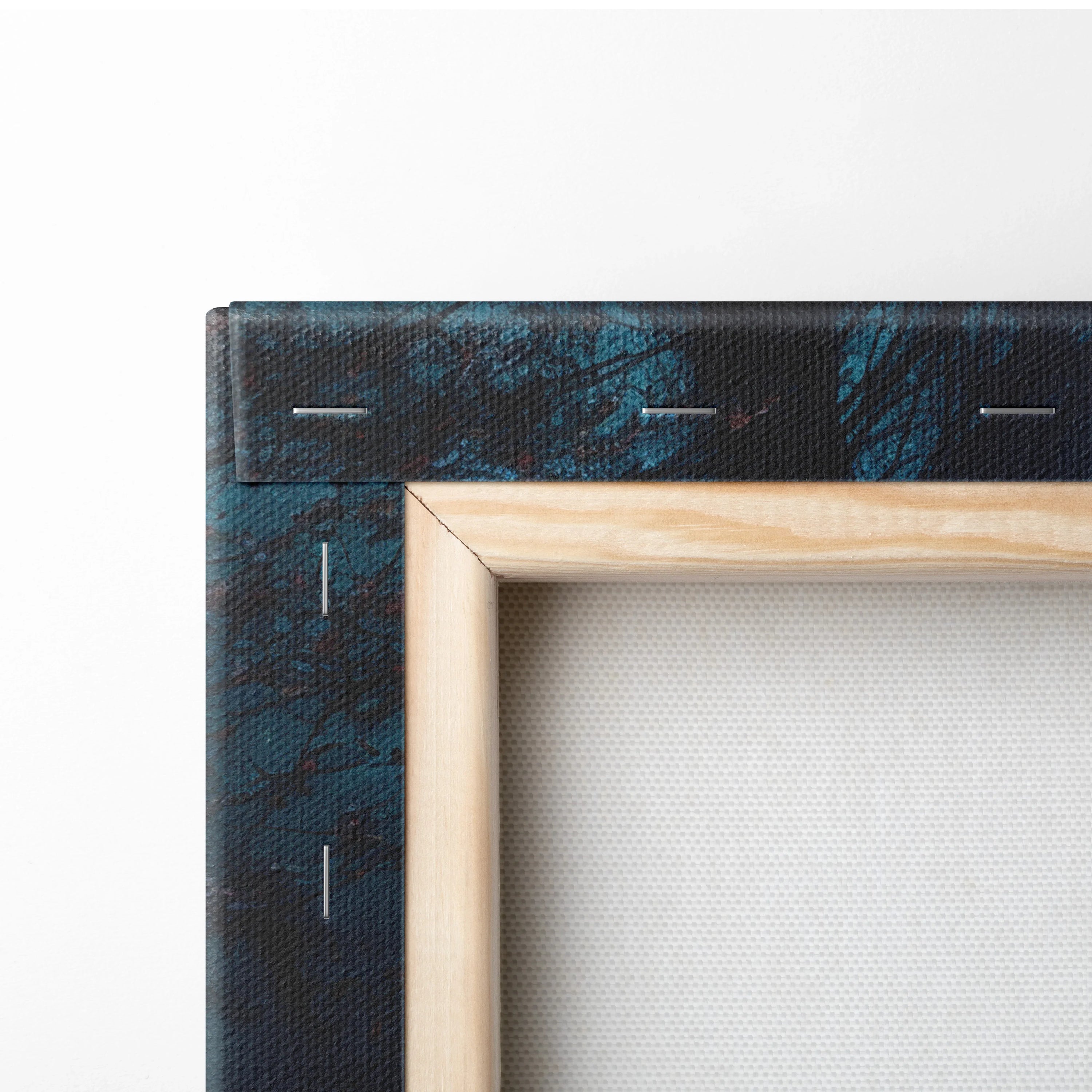 Close-up of wooden framed canvas with dark blue textured edge and taut white fabric art surface.
