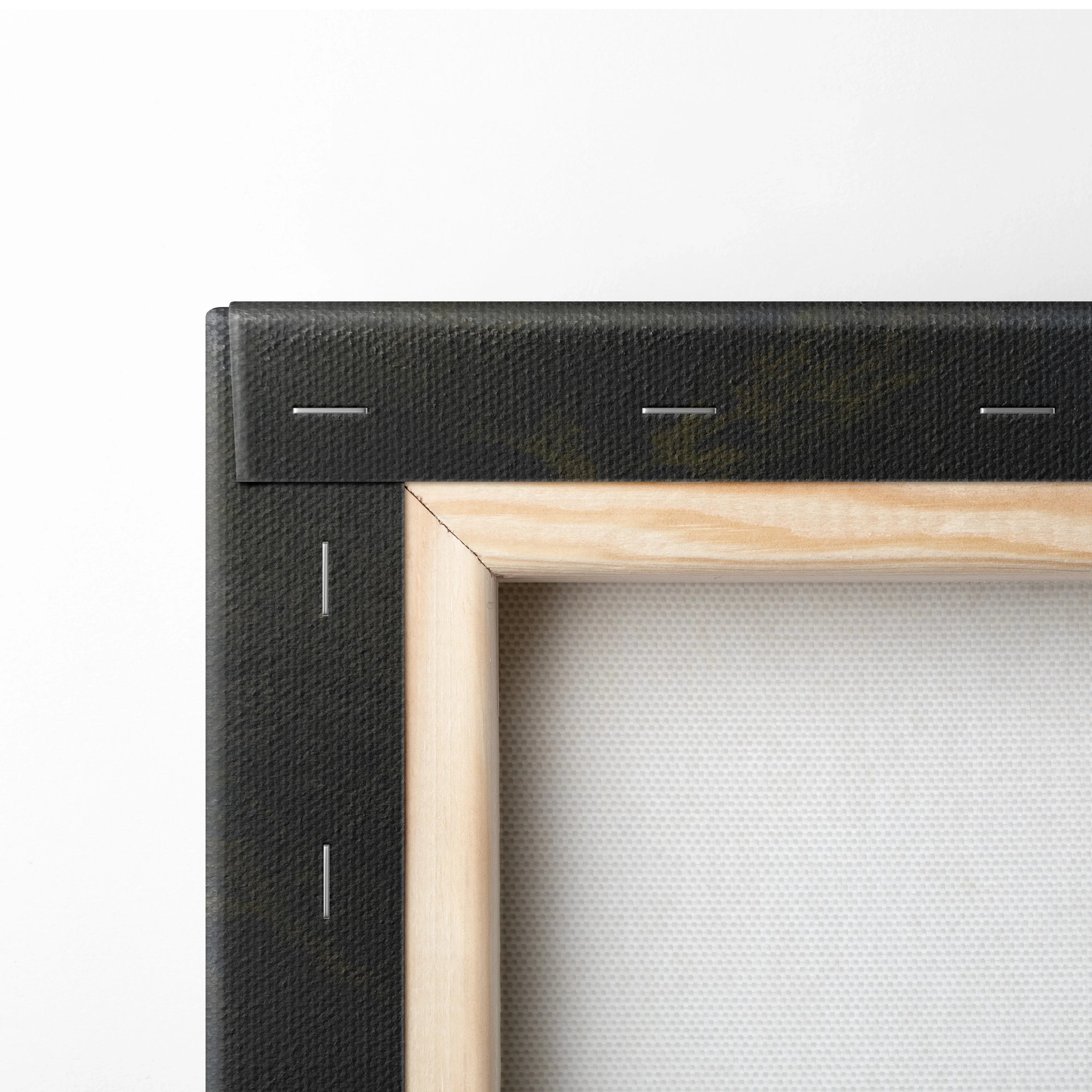 Close-up of black-stretched canvas with natural wood frame and silver staples visible on the back side.