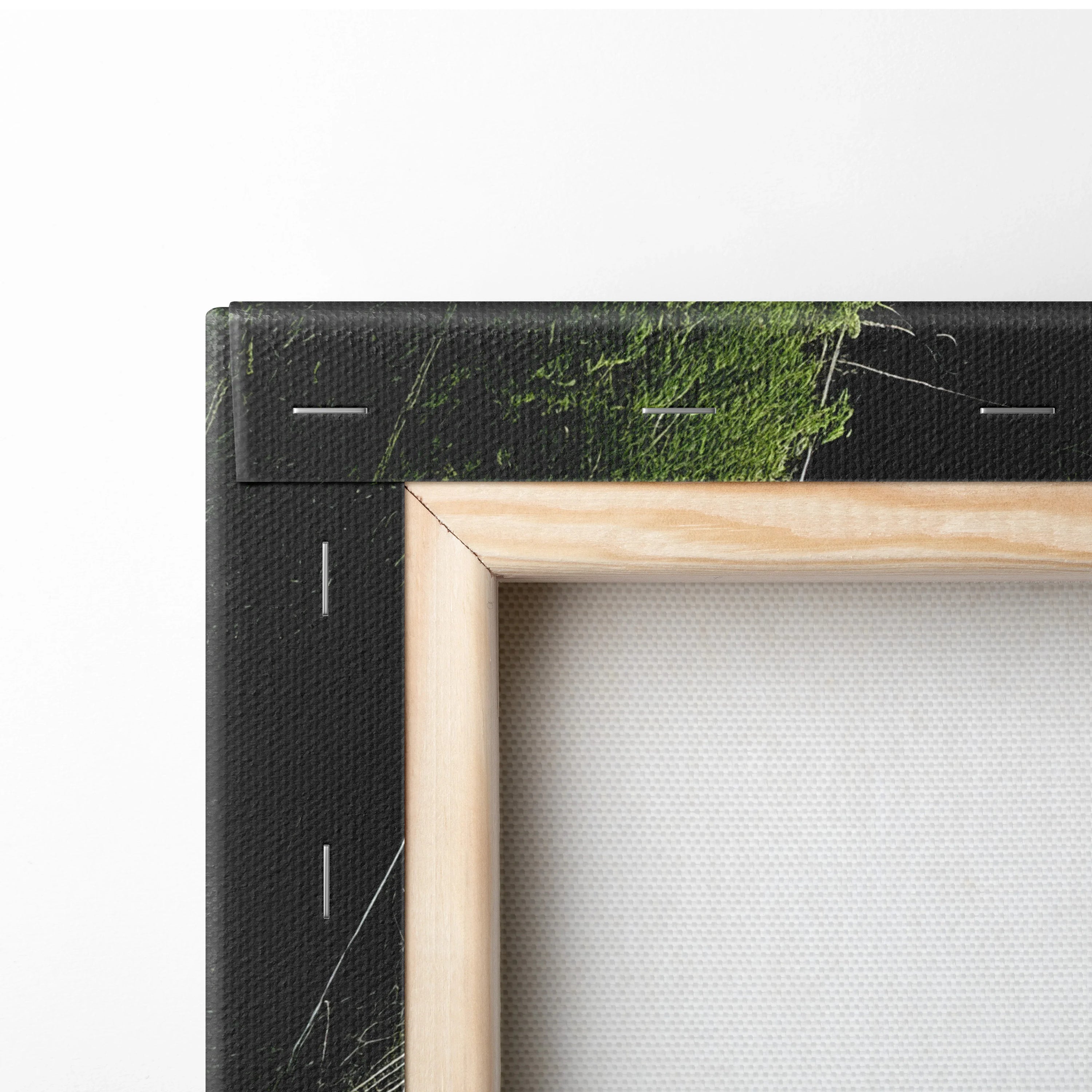 Close-up of stretched canvas wall art showing wooden frame with black forest and waterfall print edges and visible staples.