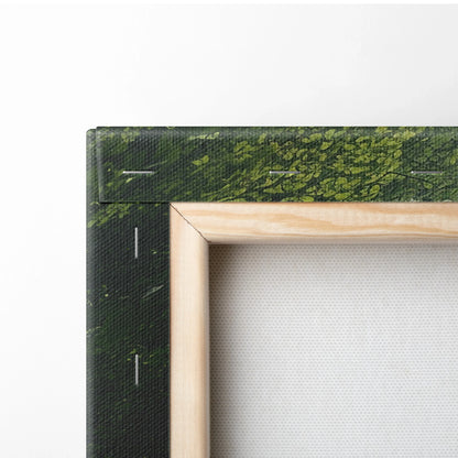 Corner of a stretched canvas wall art with a wooden frame and green forest print wrapping the edges.