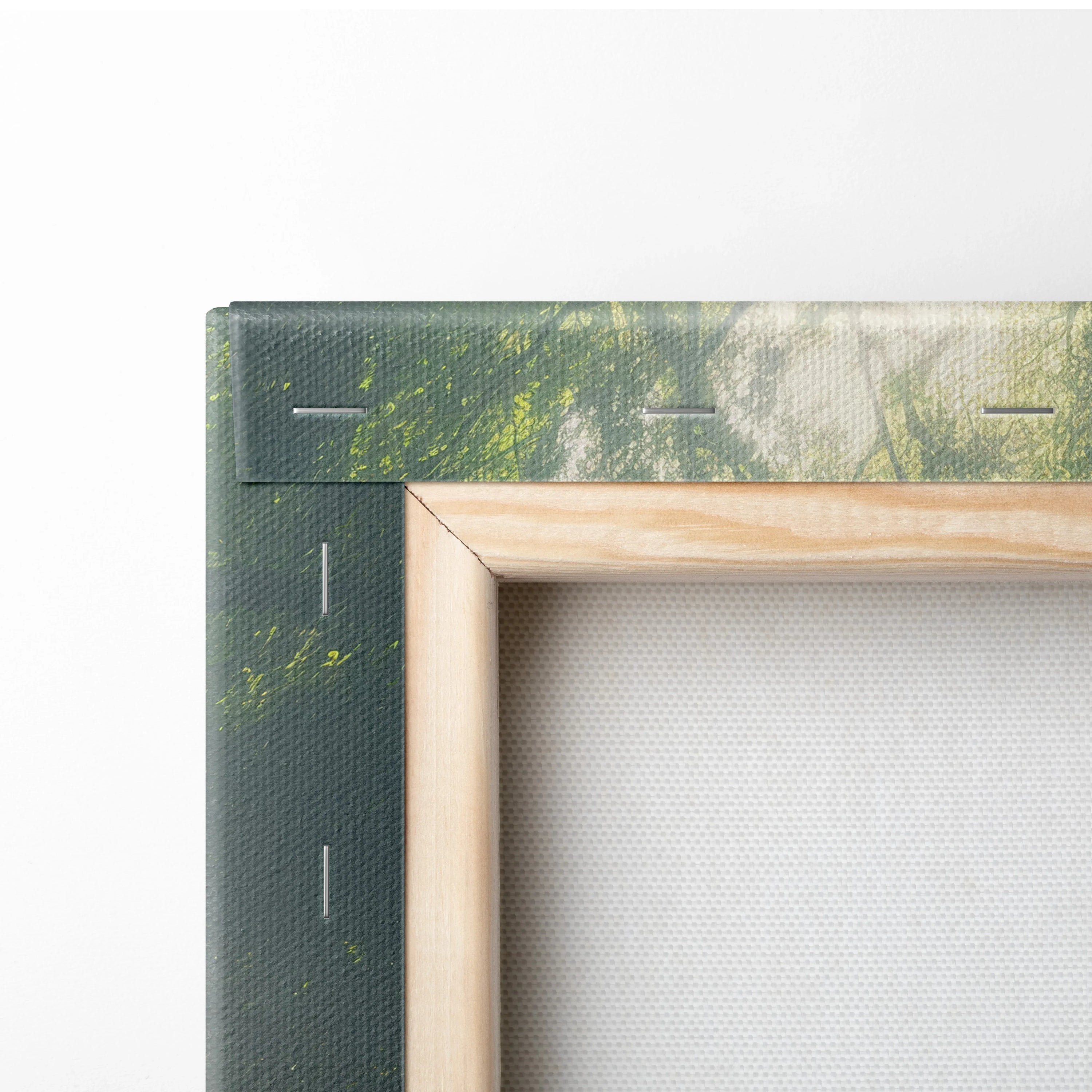 Close-up of stretched canvas art with green forest print and wooden frame edges.