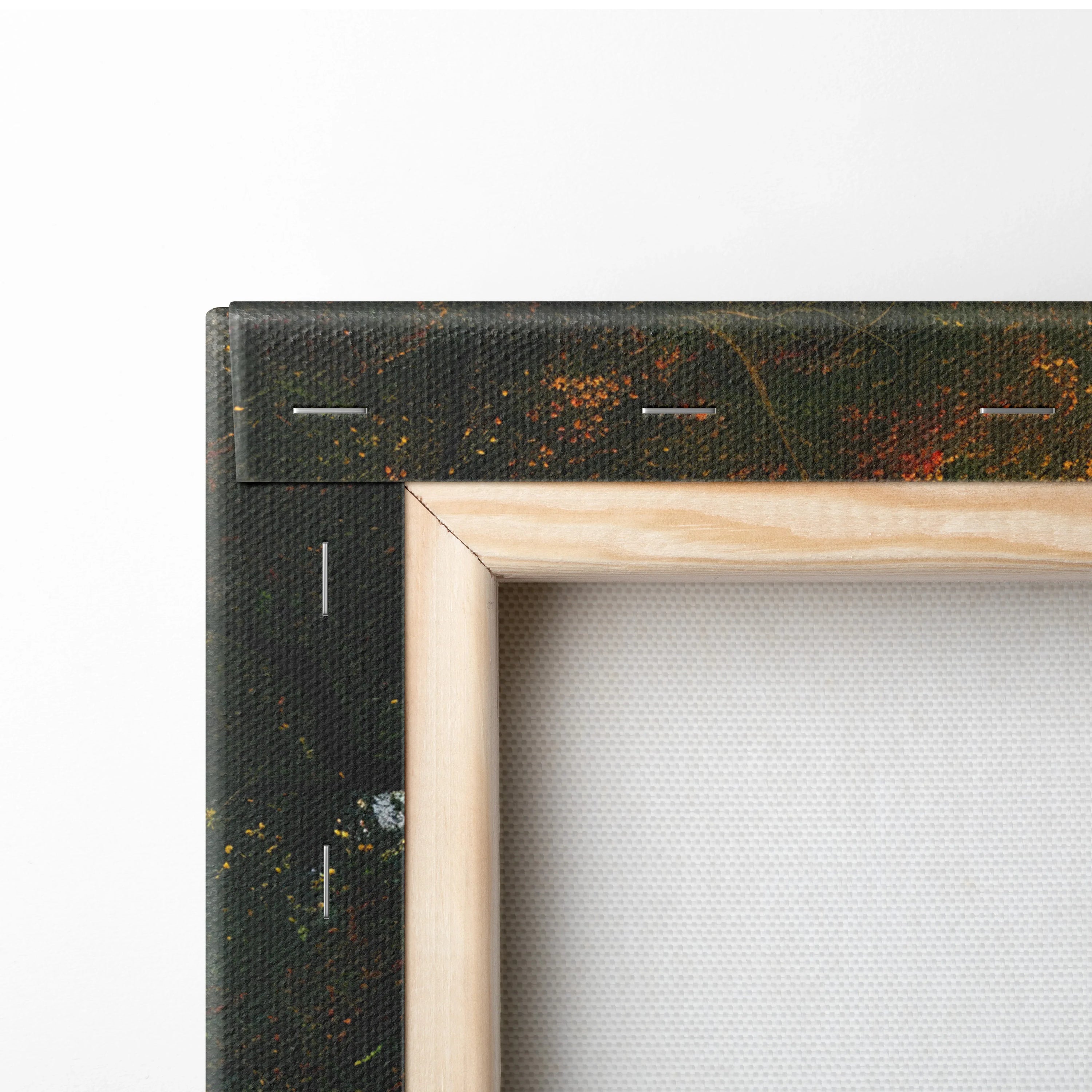 Close-up of canvas wall art corner showing wooden frame and tightly stretched white fabric with printed forest pattern edge.