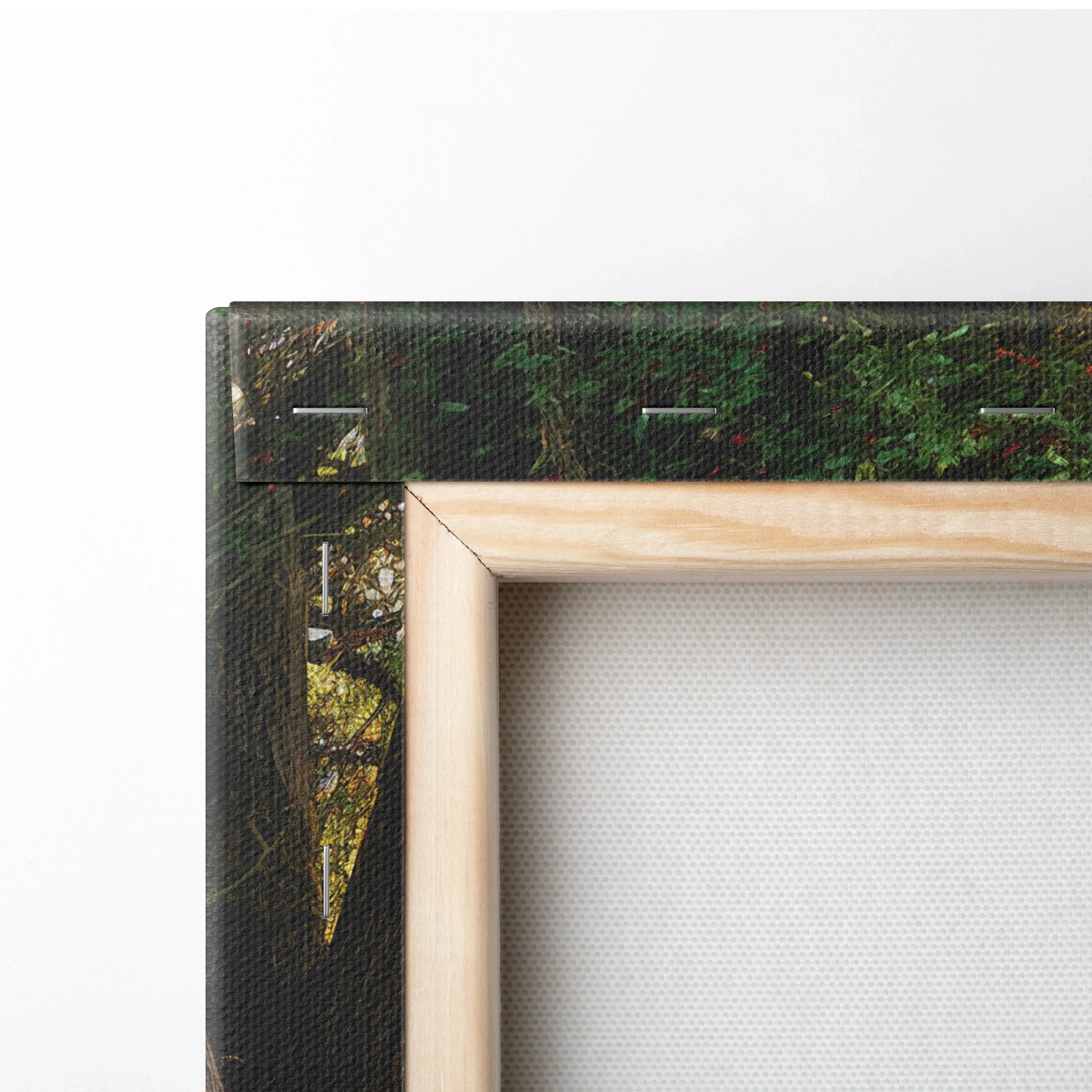 Close-up of natural wood frame corner on stretched canvas wall art with dark forest and waterfall print decor.