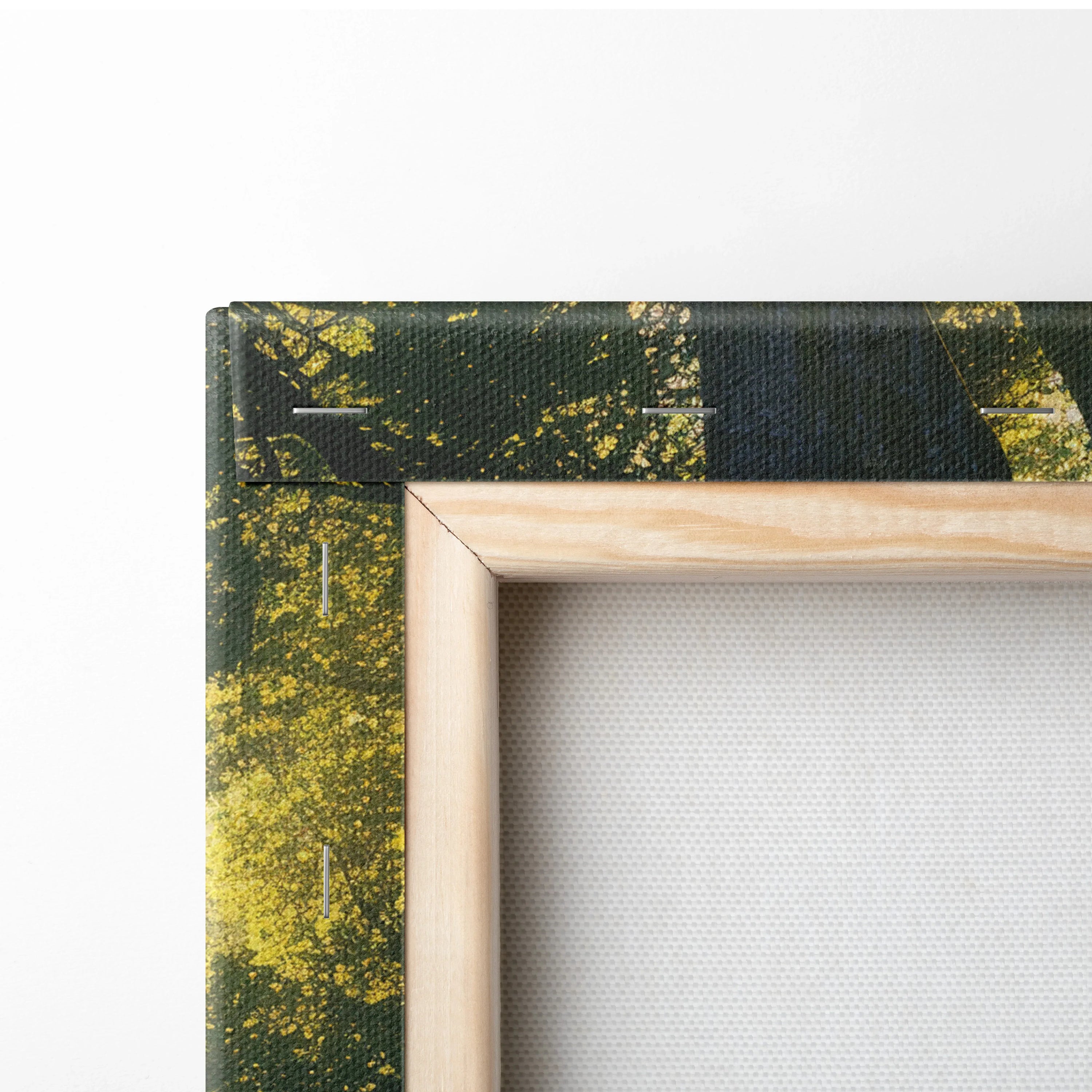 Close-up of wooden frame corner around canvas with dark green and yellow nature-themed print.