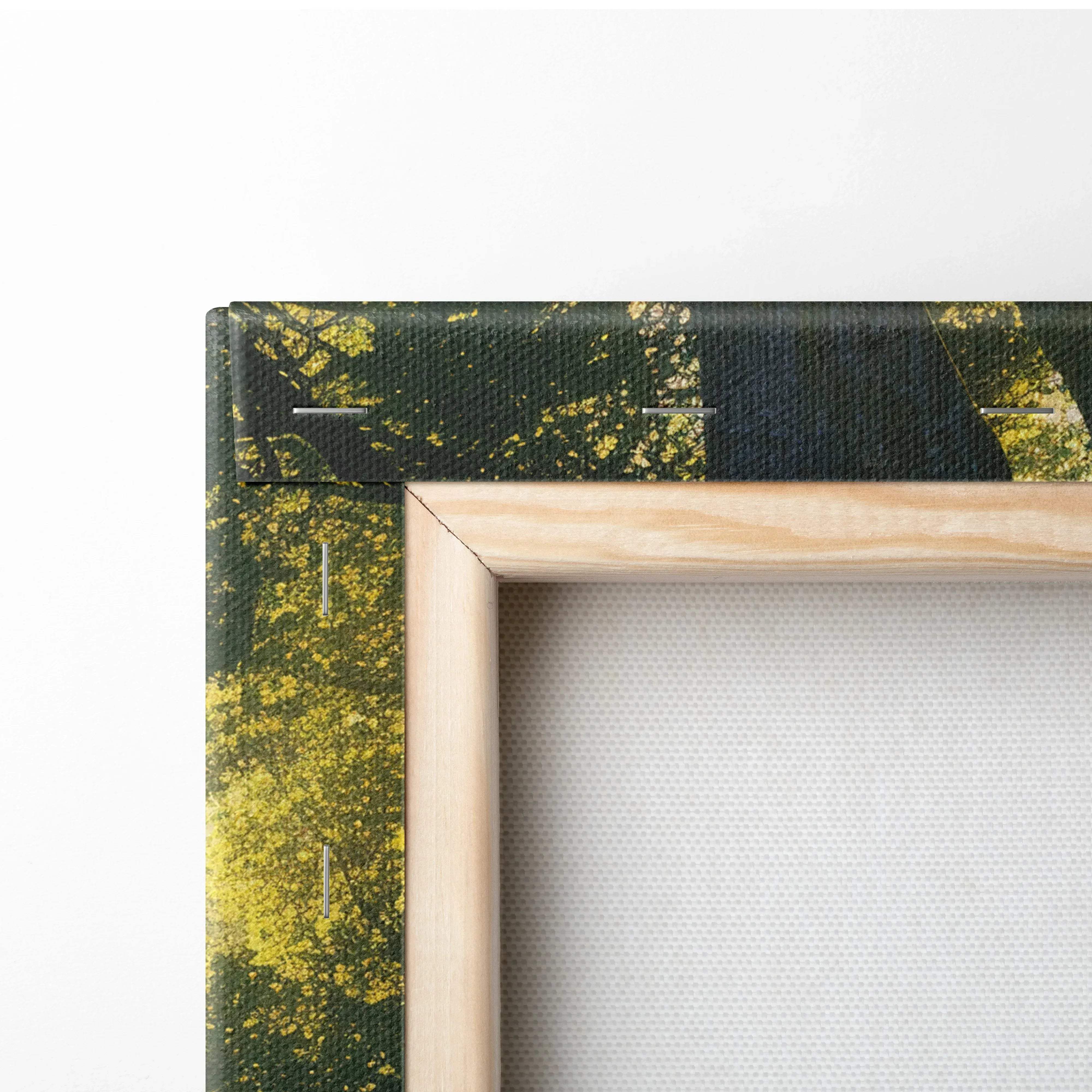 A framed canvas print featuring a forest scene with dark green trees and yellow foliage in a light wood frame