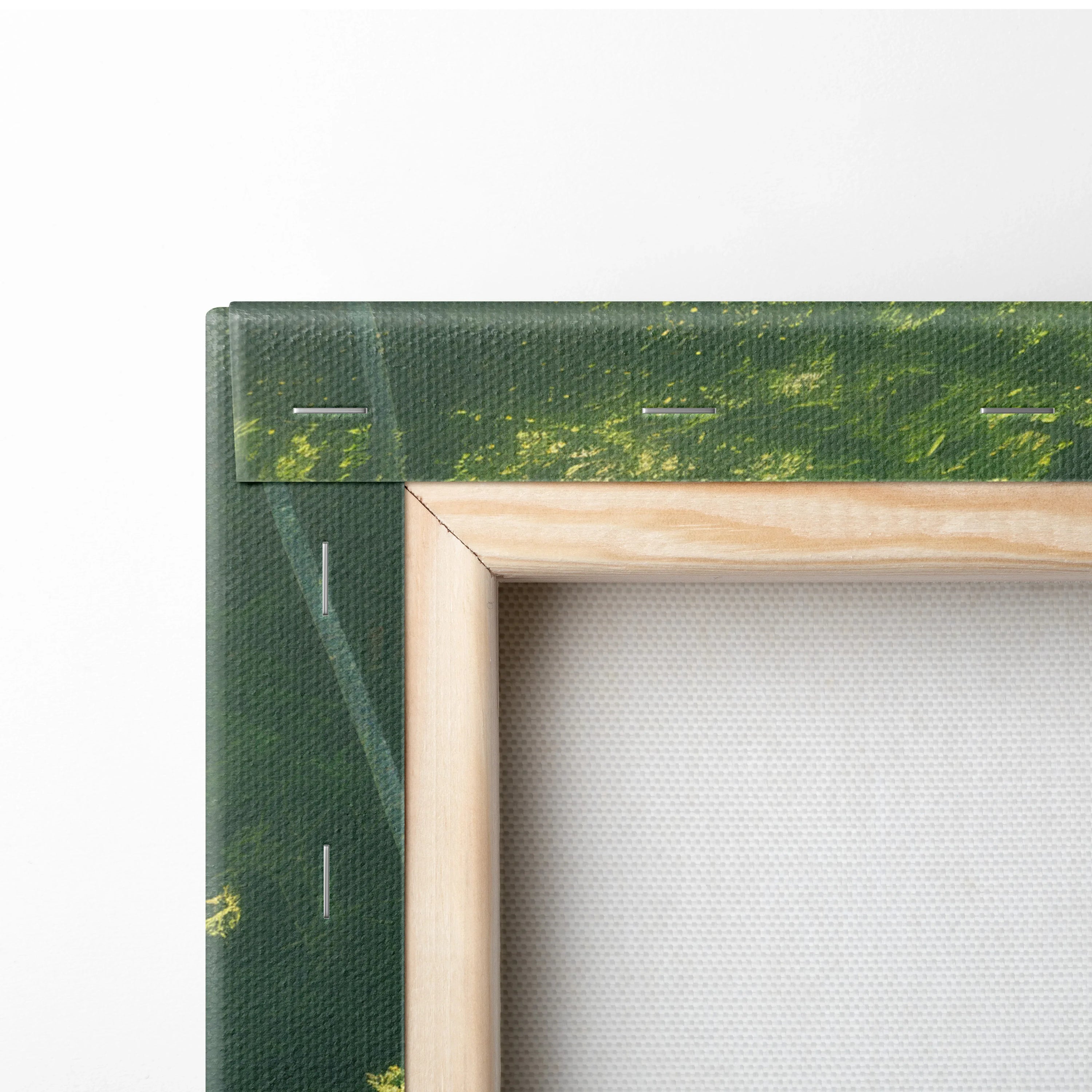 Close-up of canvas wall art corner with green forest print and natural wood frame.