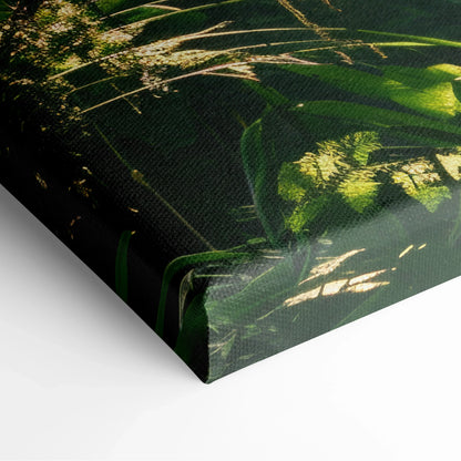 Close-up of canvas wall art featuring lush green tropical forest foliage with sunlight filtering through leaves.