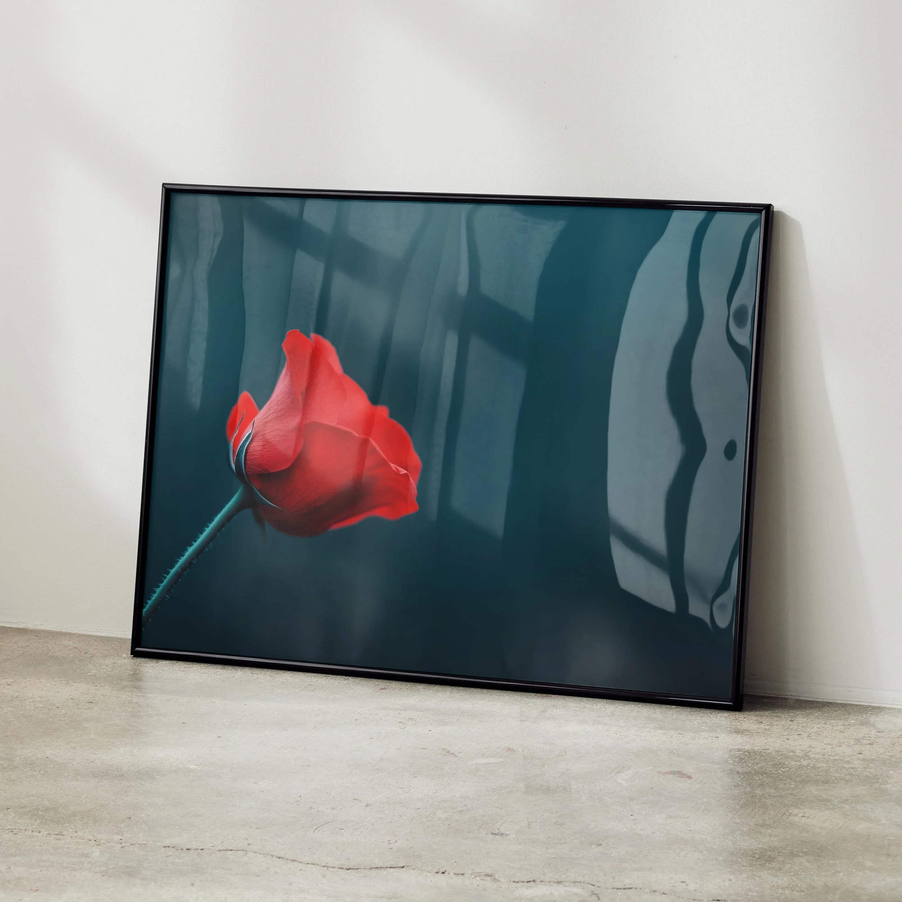 Vibrant red rose floral digital art poster in black frame leaning on white wall, modern wall art.