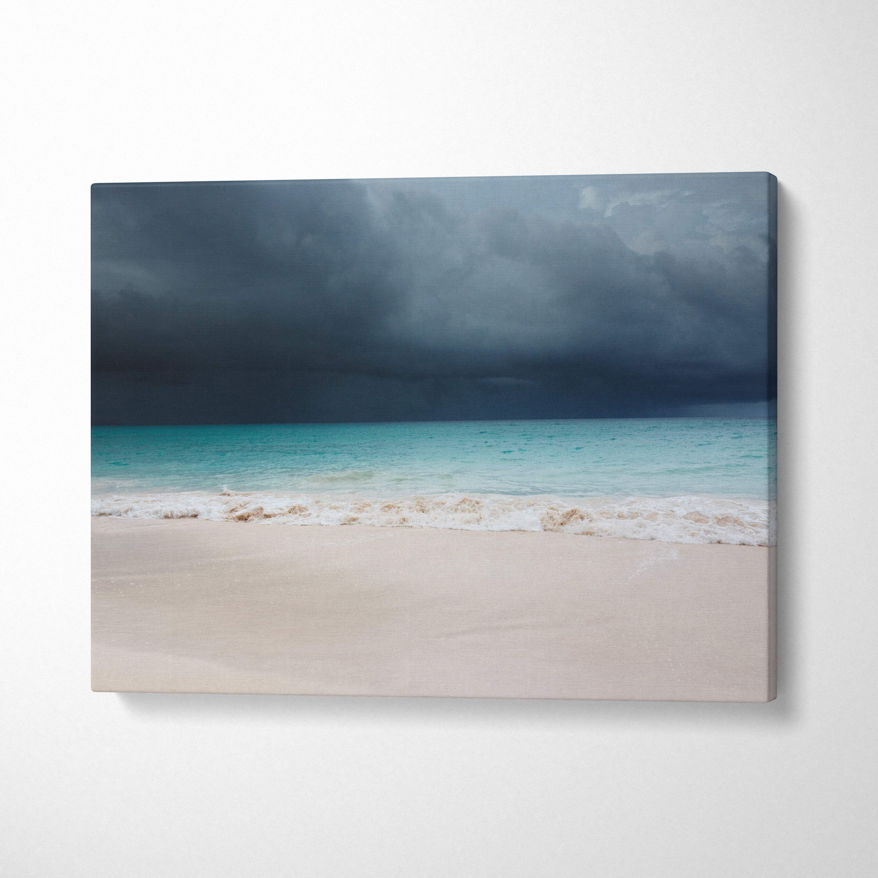 A rectangular canvas print of stormy beach art featuring turquoise waves white sand and dark thunderclouds
